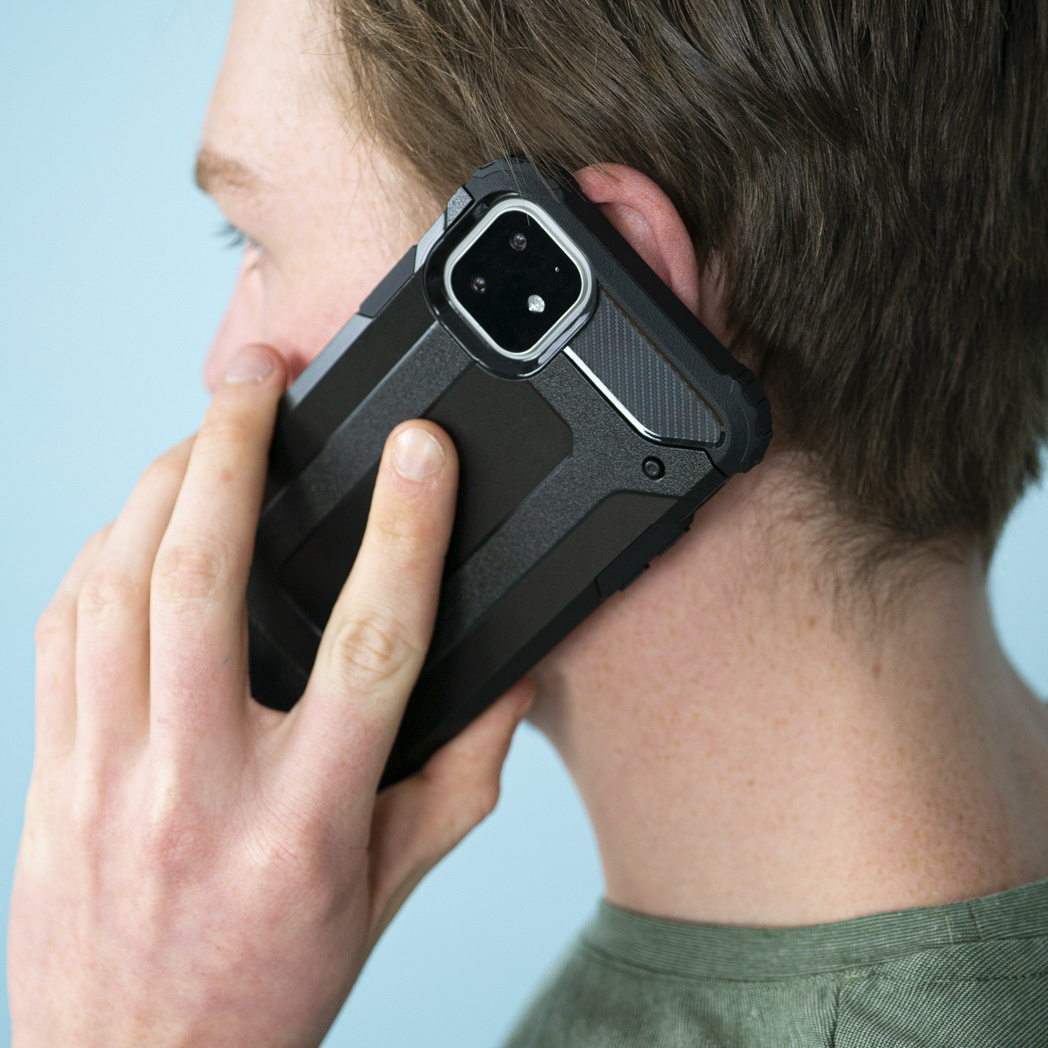 Persona che tiene un telefono in una custodia nera all'orecchio. Sfondo azzurro.