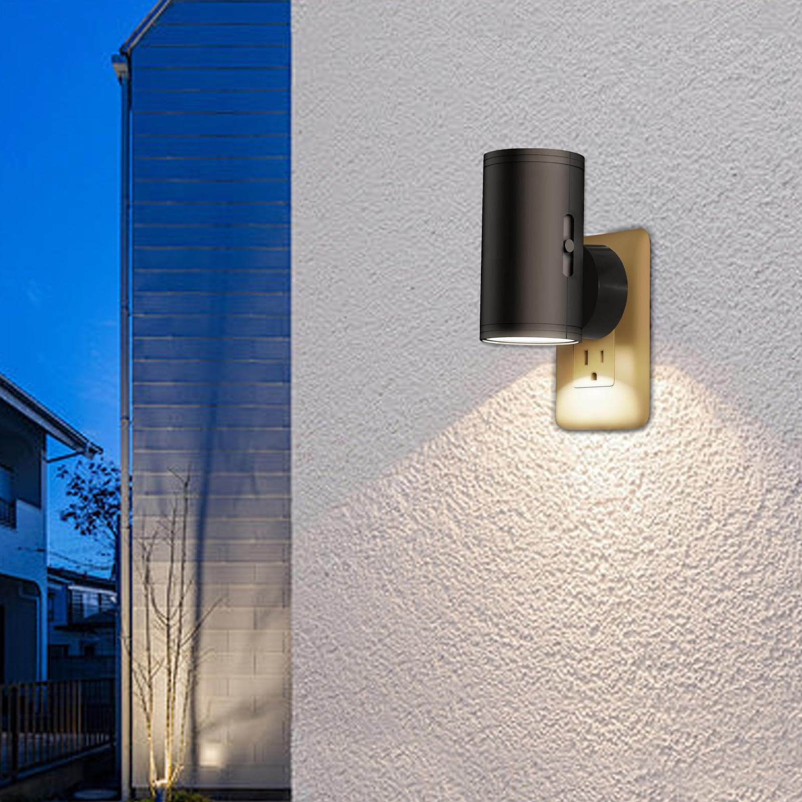 Außenwand mit einer schwarzen zylindrischen Lampe an einer beigen Steckdose. Die Szene ist in der Dämmerung.