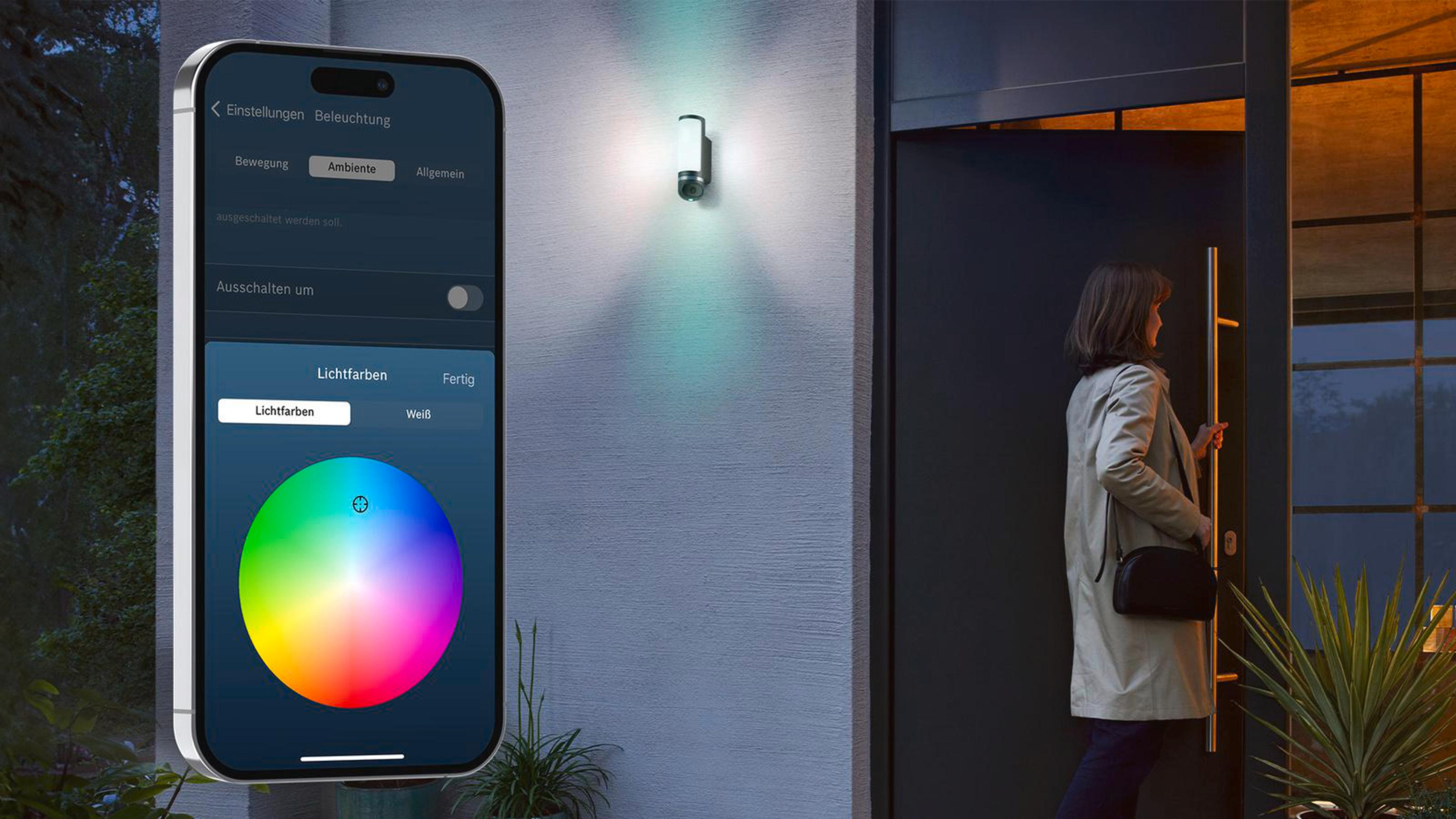 Eine Frau öffnet eine Tür. Ein Telefon zeigt eine App mit Farbeinstellungen, die ein Außenlicht steuert.