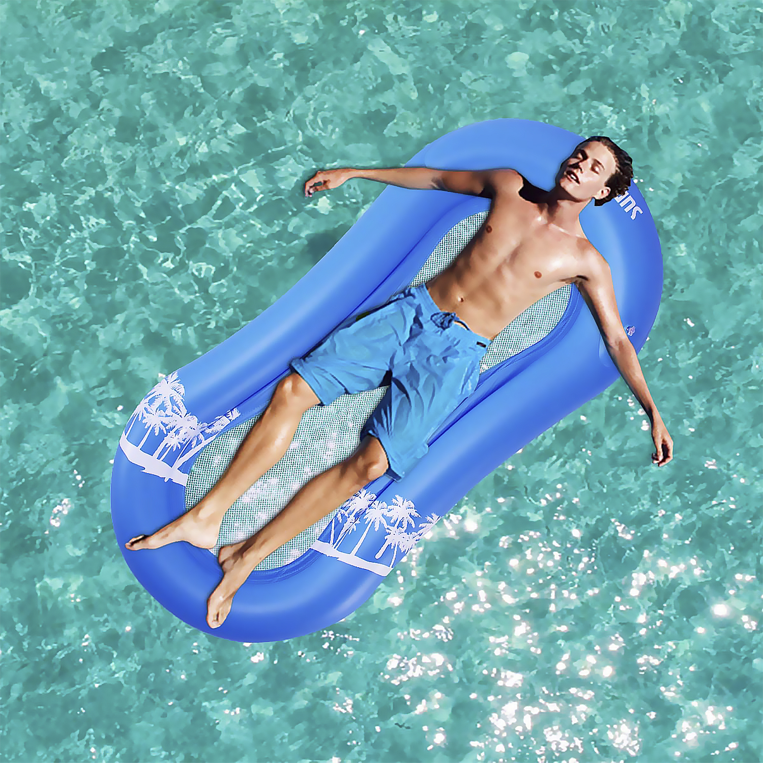 Uomo sdraiato su un galleggiante gonfiabile blu in acqua blu trasparente. Il galleggiante ha un design a palme.