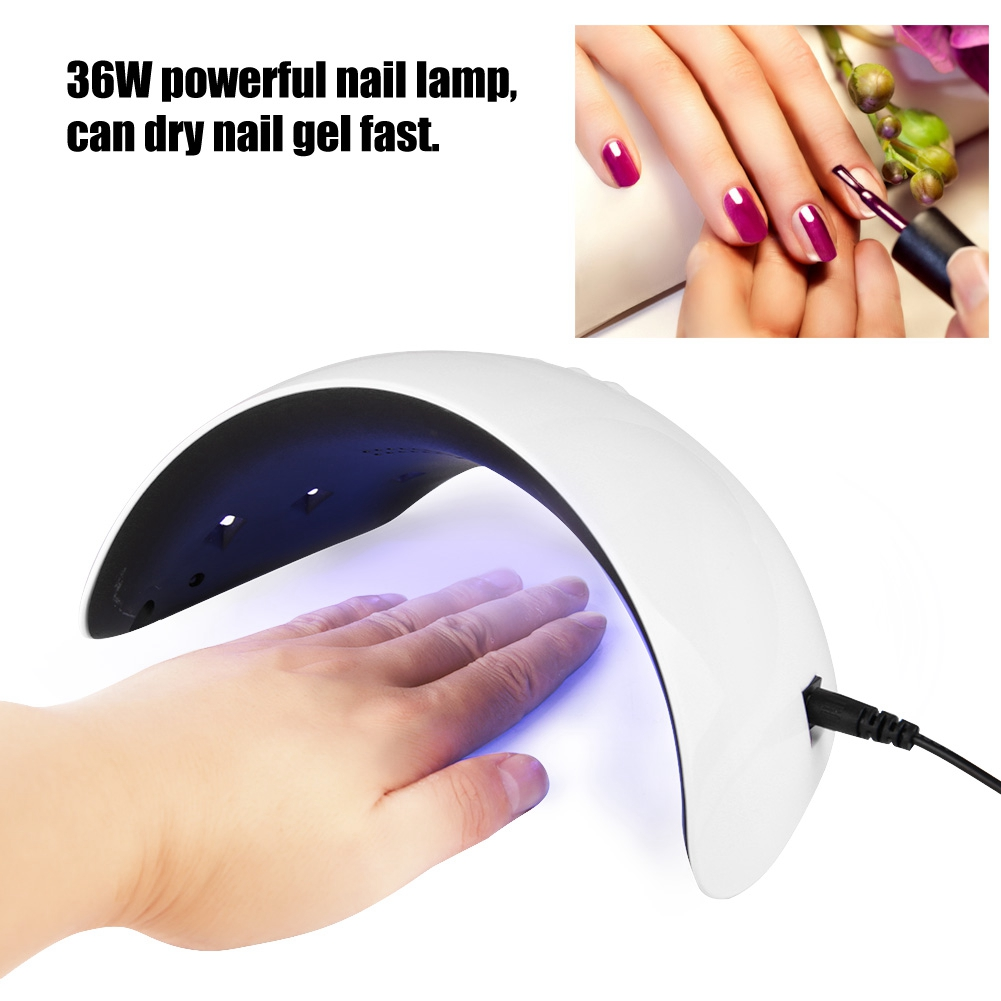 Eine weiße Nagellampe mit einer Hand darin, mit einer Nahaufnahme einer Hand, die Nagellack aufträgt.