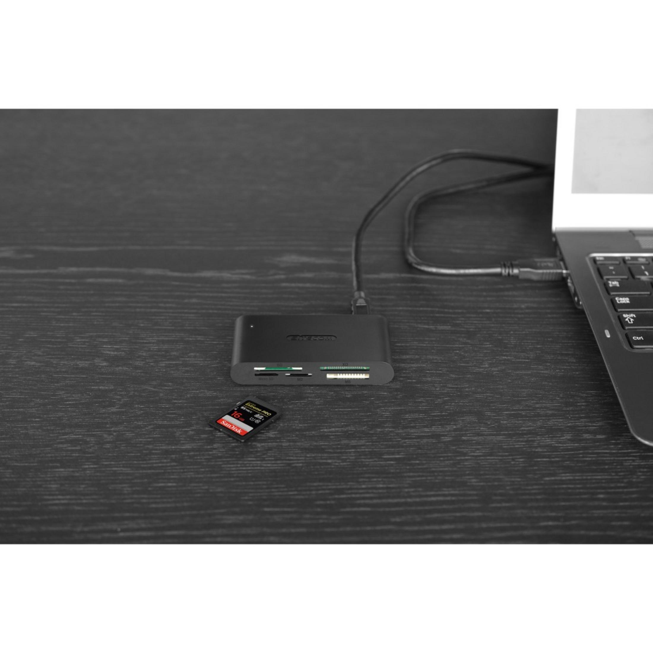 Un lettore di schede nero collegato a un laptop tramite USB. Una scheda SD è accanto.