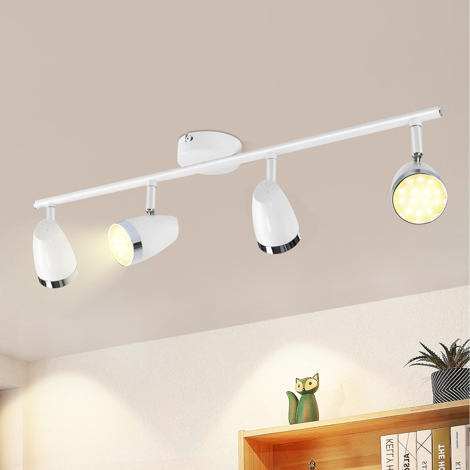 Un apparecchio di illuminazione a binario bianco con quattro faretti, montato su un soffitto bianco.