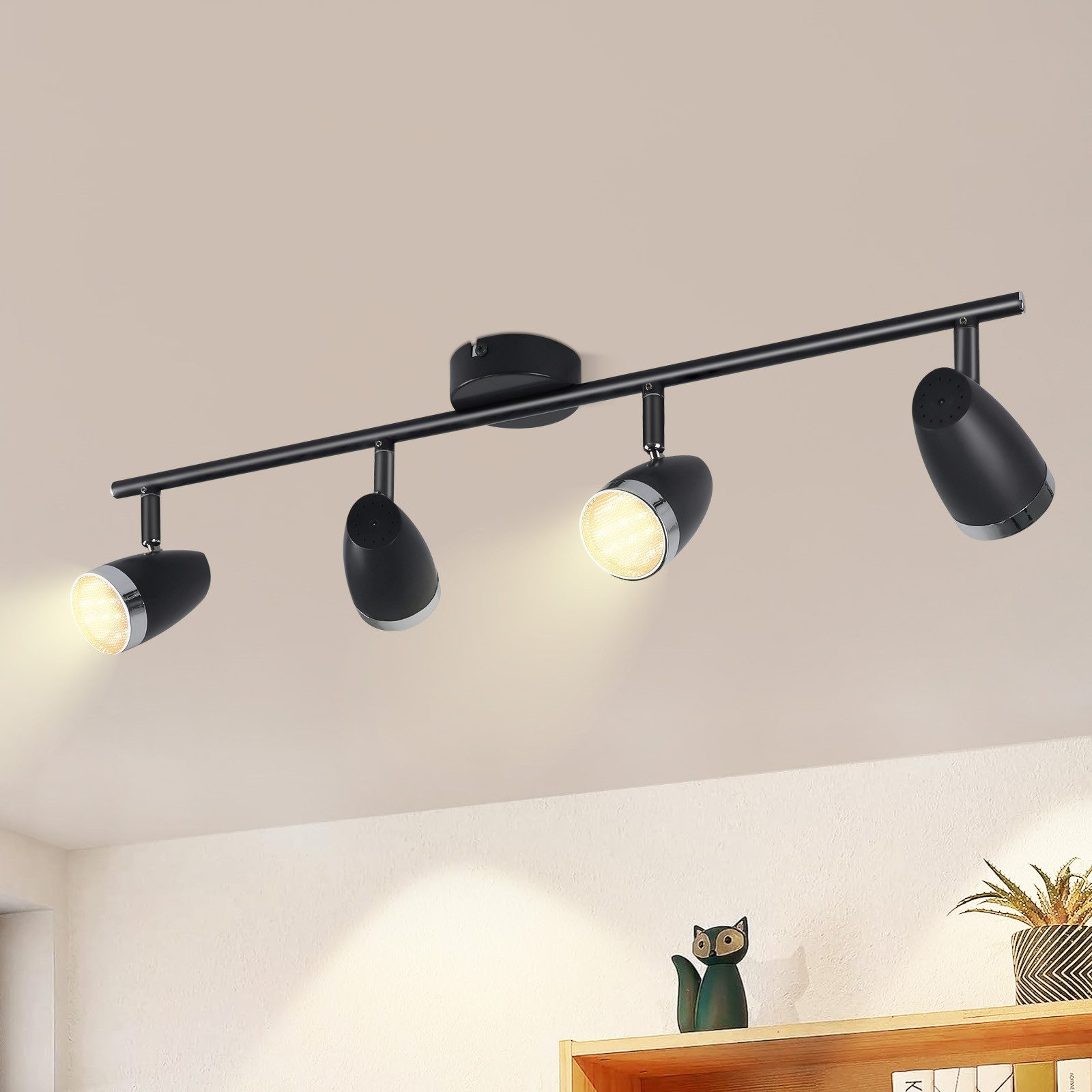 Faretti neri a soffitto su una guida, quattro faretti, su un soffitto bianco.