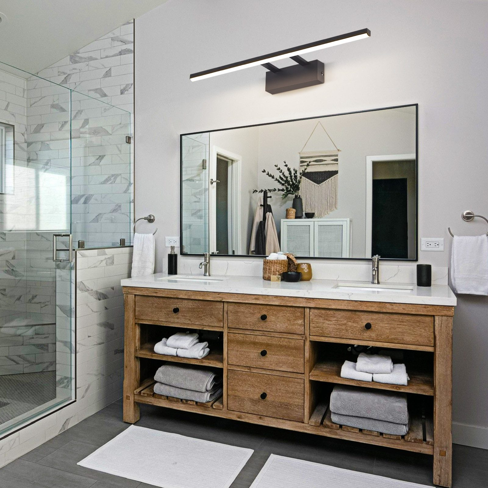 Bagno moderno con specchio grande, mobile in legno e lunga lampada sopra.