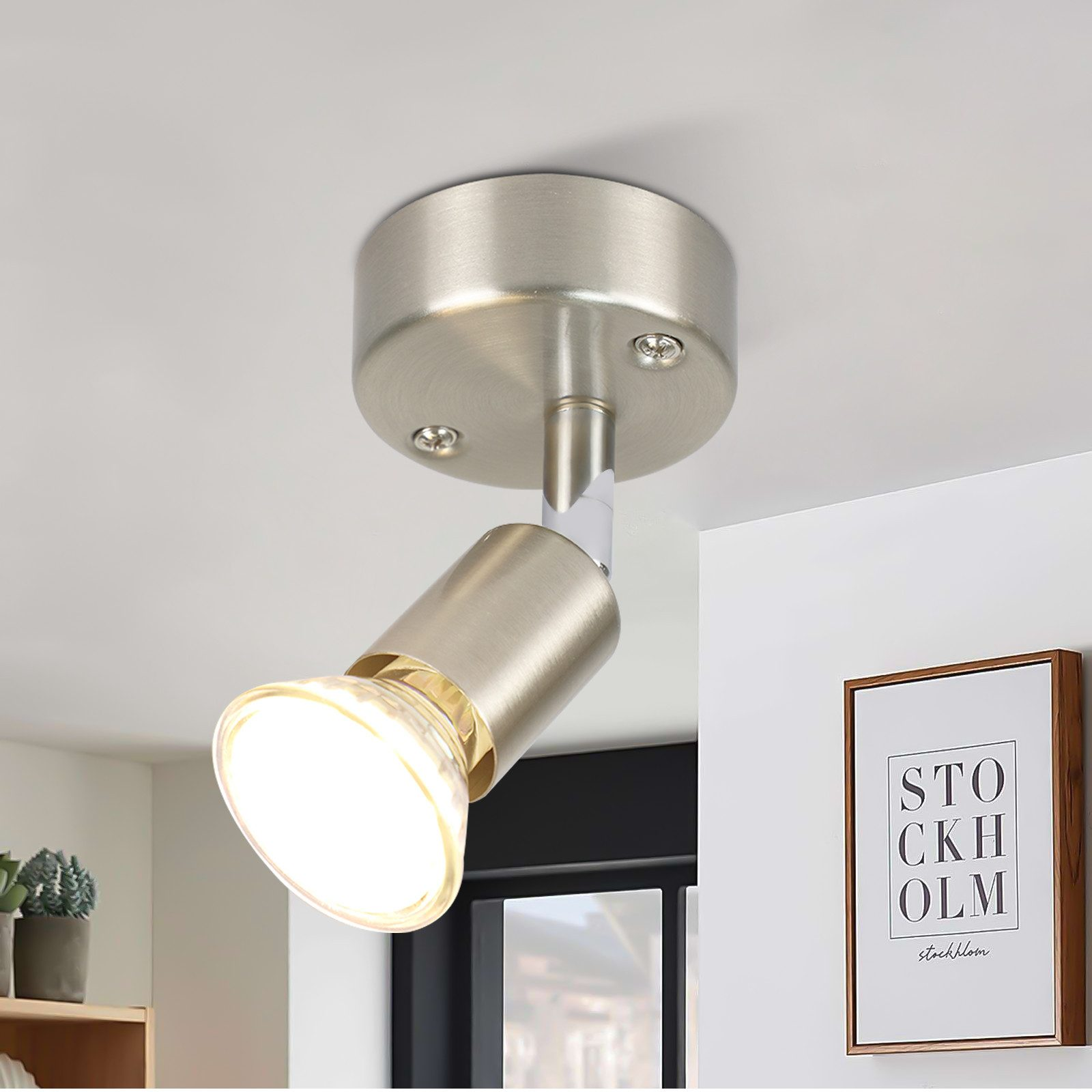 Faretto da soffitto argentato con luce intensa. Soffitto bianco, sfondo neutro.