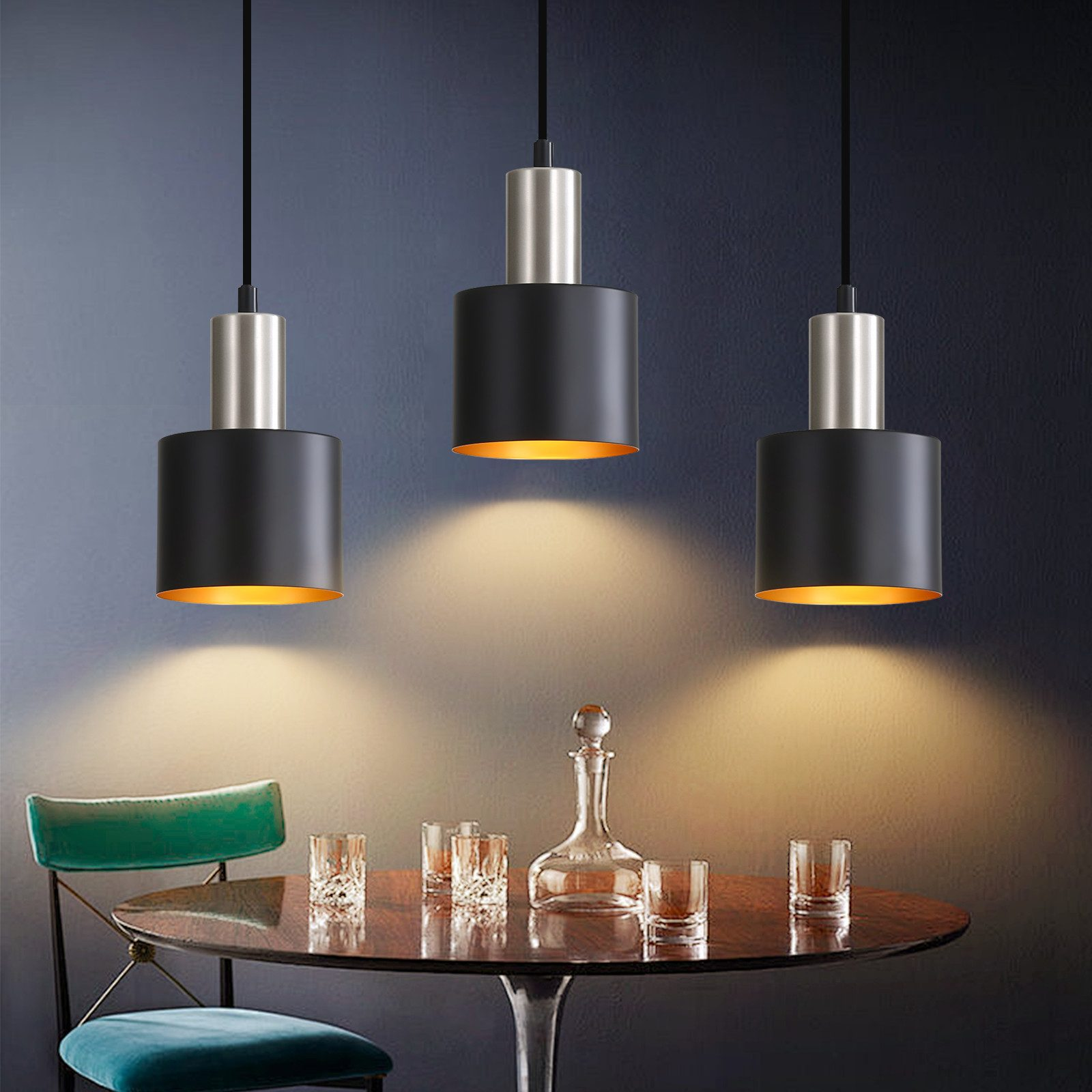 Trzy czarne lampy wiszące ze złotymi wnętrzami nad stołem.