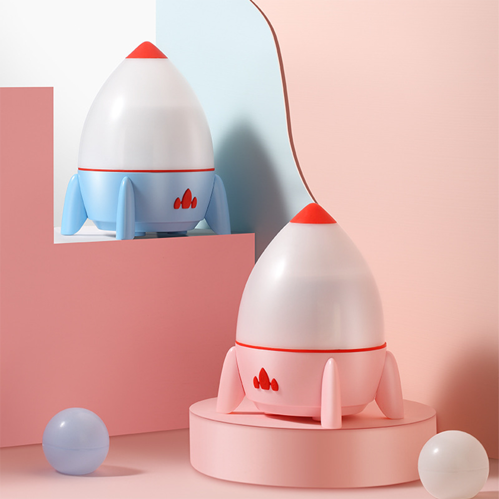 Zwei raketenförmige Nachtlichter, eines blau und eines rosa, auf einer rosa und blauen Oberfläche.