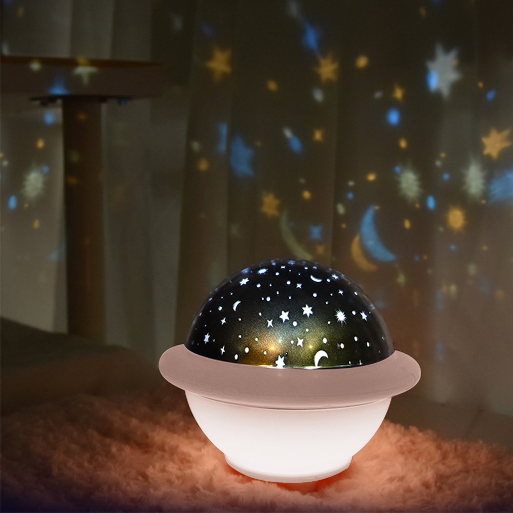 Ein Sternennacht-Lichtprojektor. Es ist weiß mit einer dunklen Kuppel, die Sterne zeigt. Auf rosa Pelz gelegt.