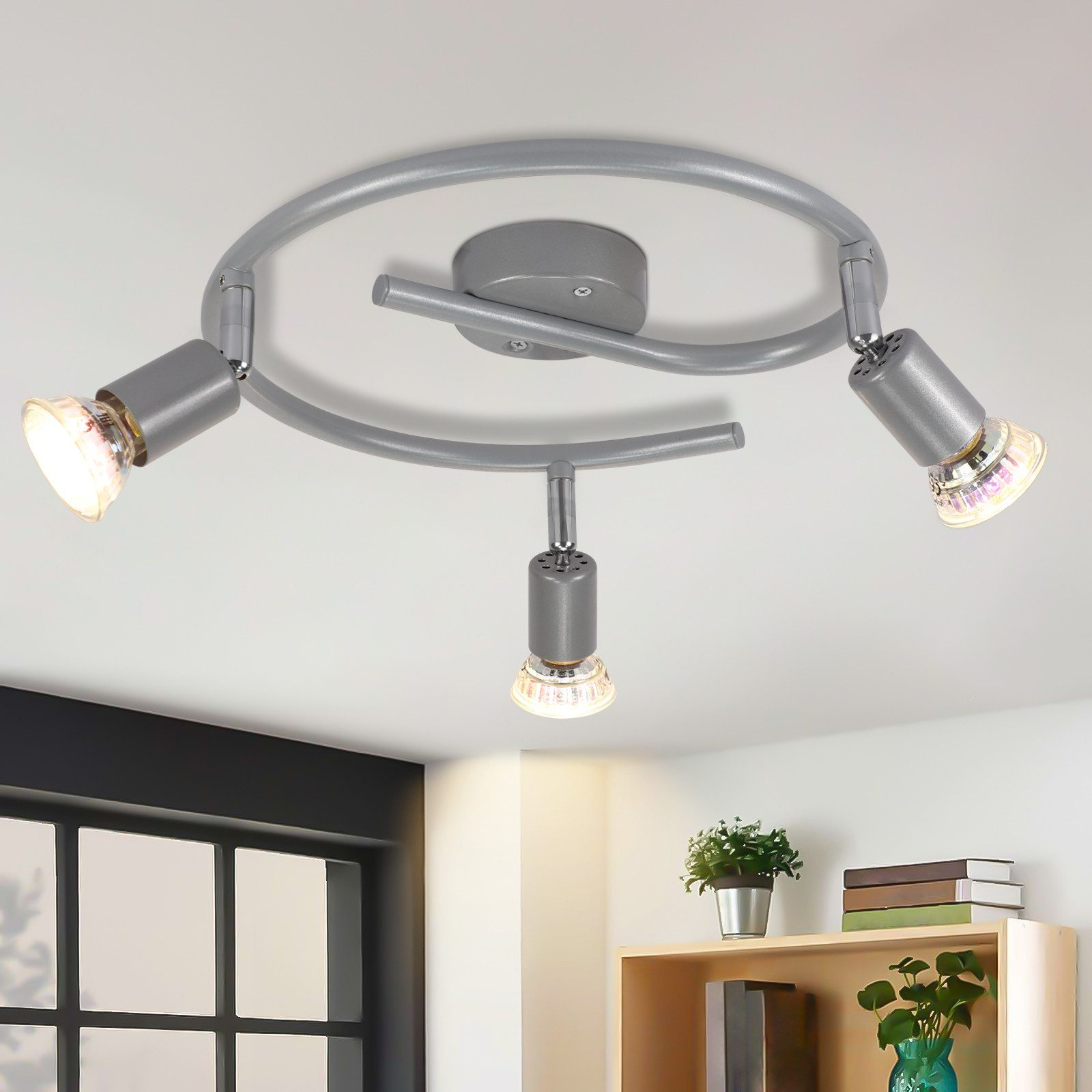 Apparecchio di illuminazione a soffitto a tre luci con teste regolabili, montato su un soffitto bianco.