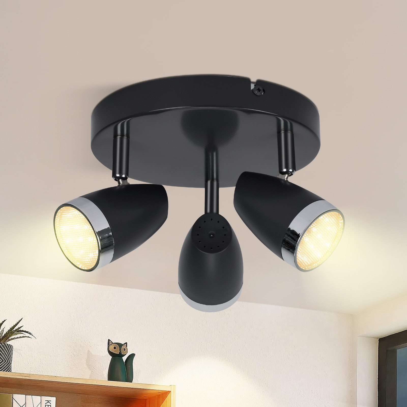 Plafoniera nera con tre faretti orientabili, montata su un soffitto bianco.