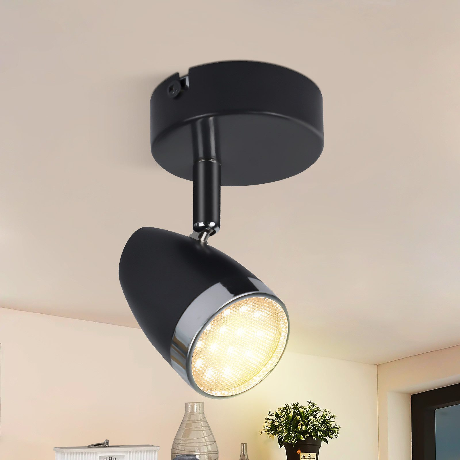 Faretto nero regolabile su un soffitto bianco. La luce è accesa.