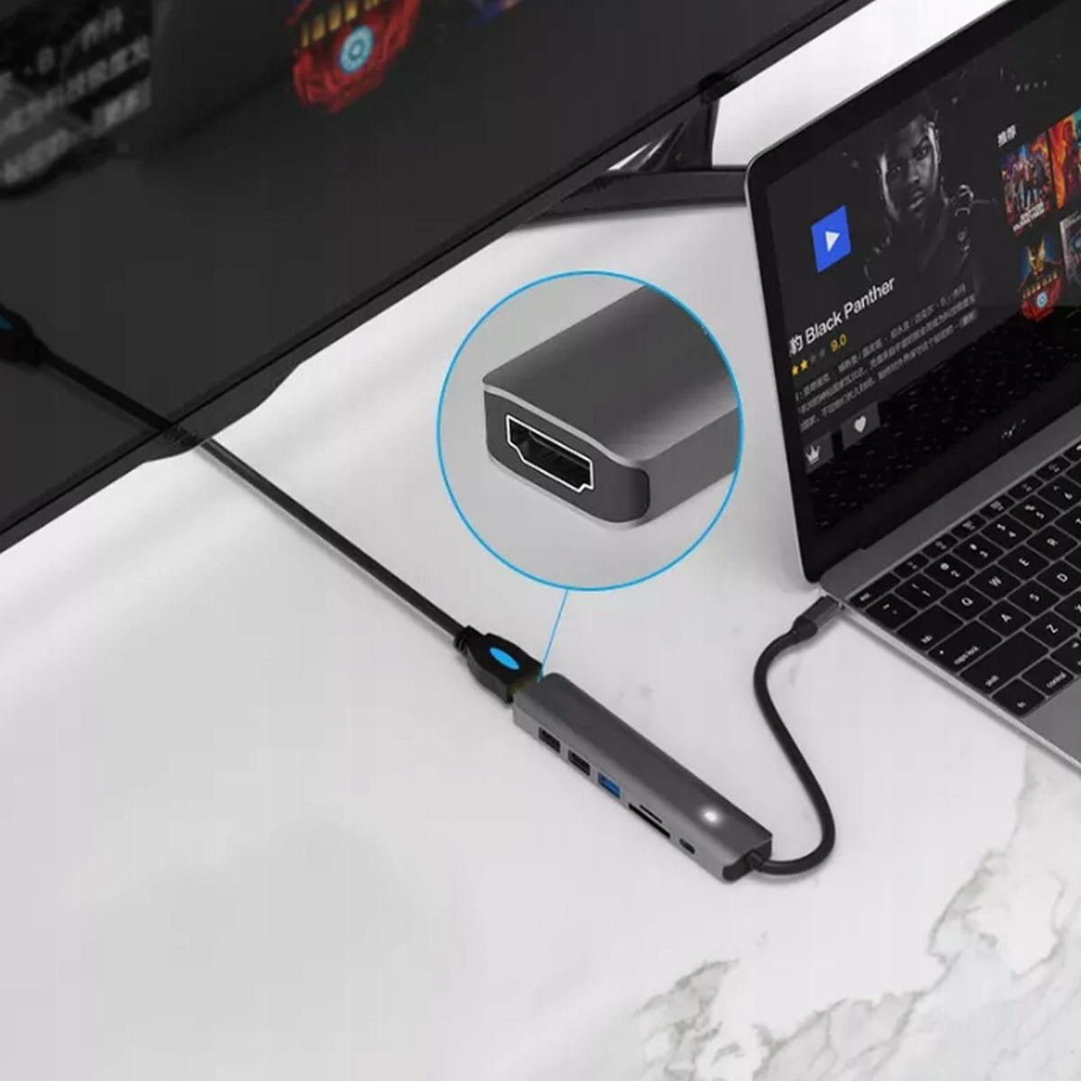 Koncentrator USB-C podłączony do laptopa i monitora, z widocznymi innymi portami. Konfiguracja jest na białym biurku.