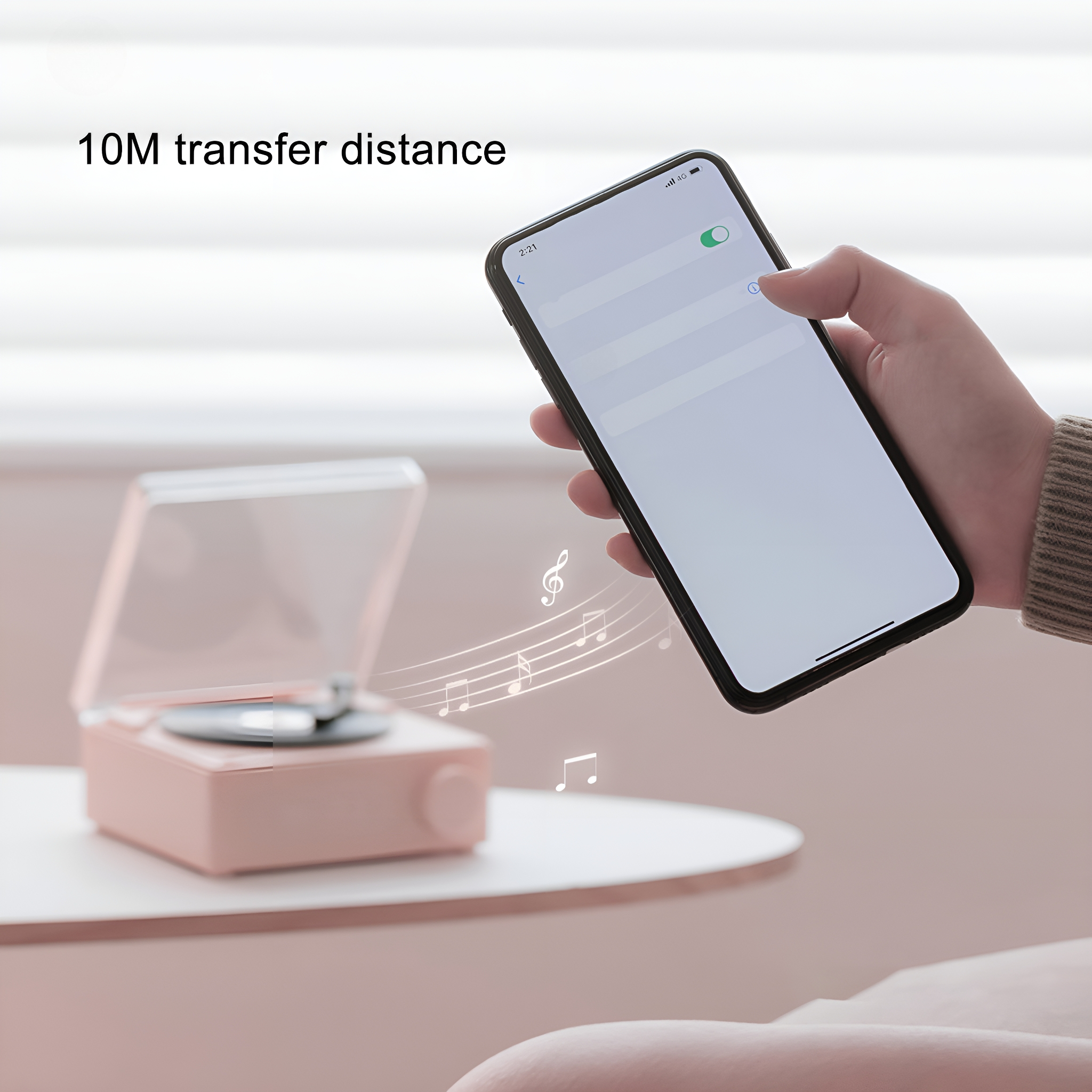 Hand hält Telefon in der Nähe eines rosa Musikplayers mit Noten. Text oben ist "10M Übertragungsdistanz".