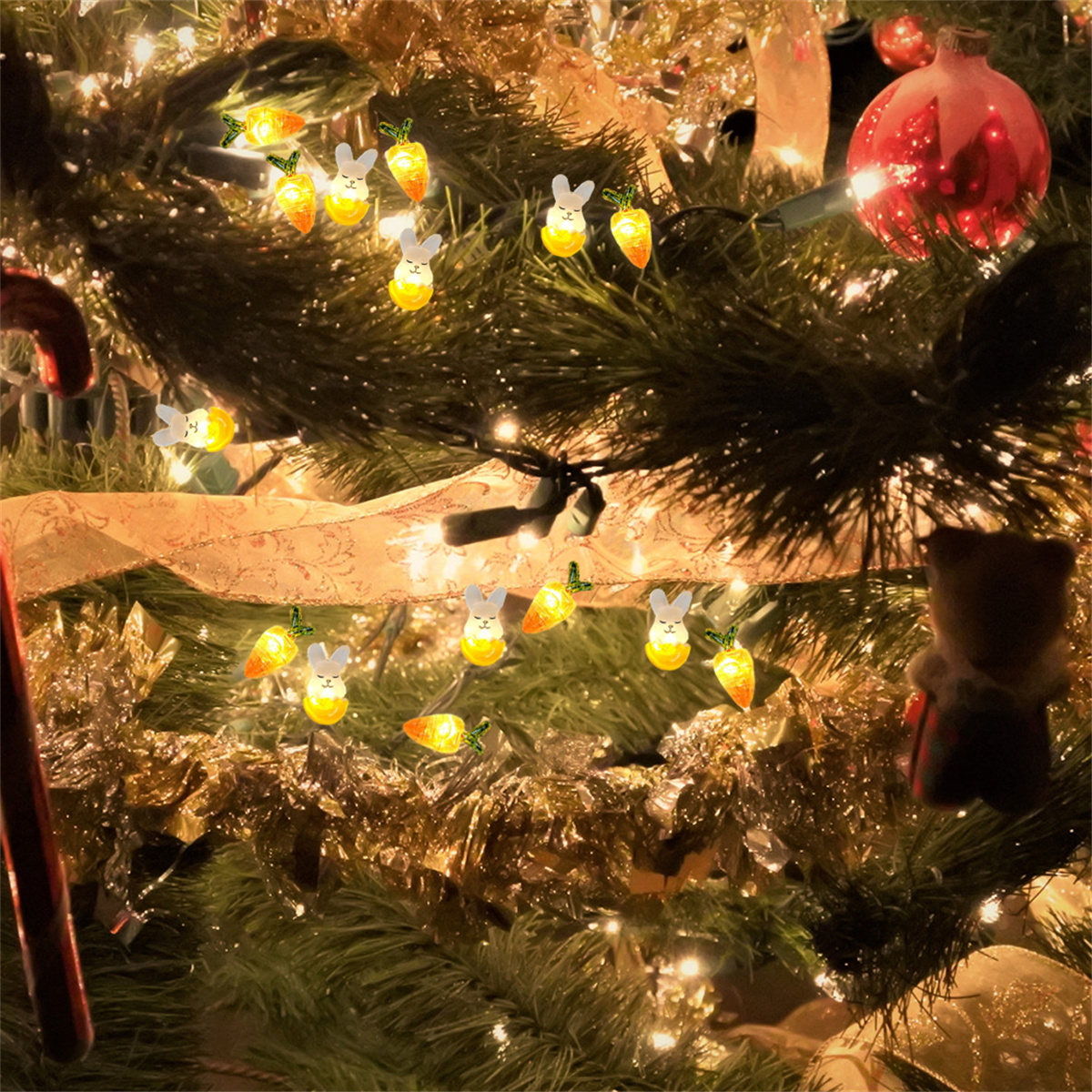 Weihnachtsbaum mit Hasenlichtern und goldenen Girlanden geschmückt. Es gibt einen roten Schmuck.