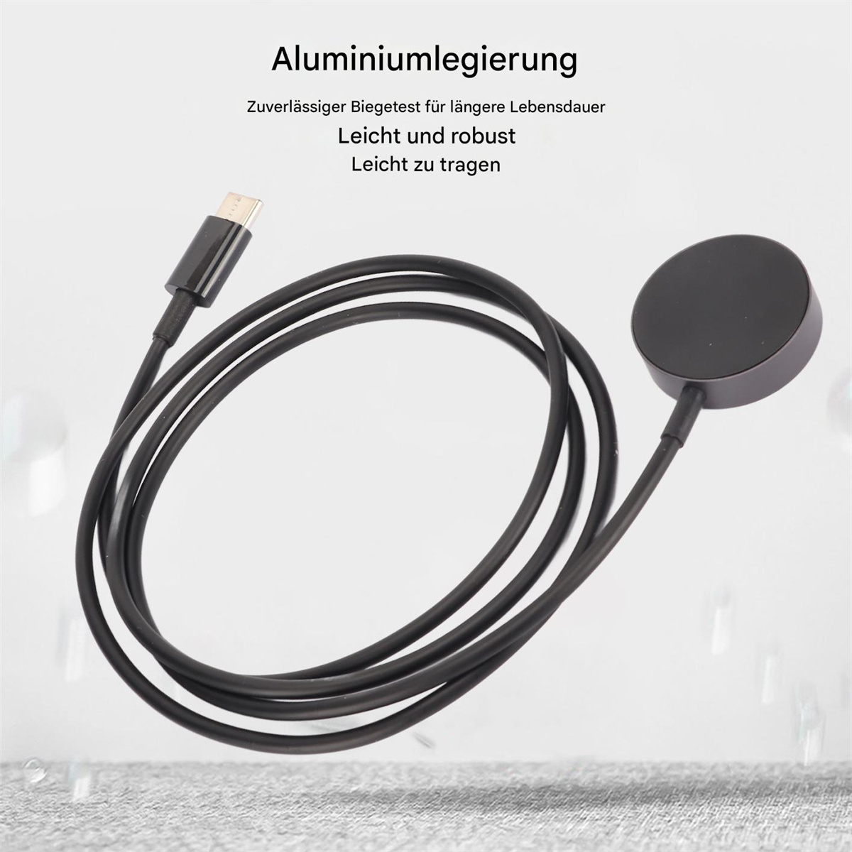 Ein schwarzes, rundes Ladepad und ein schwarzes USB-Kabel. Der Text lautet 'Aluminiumlegierung'.