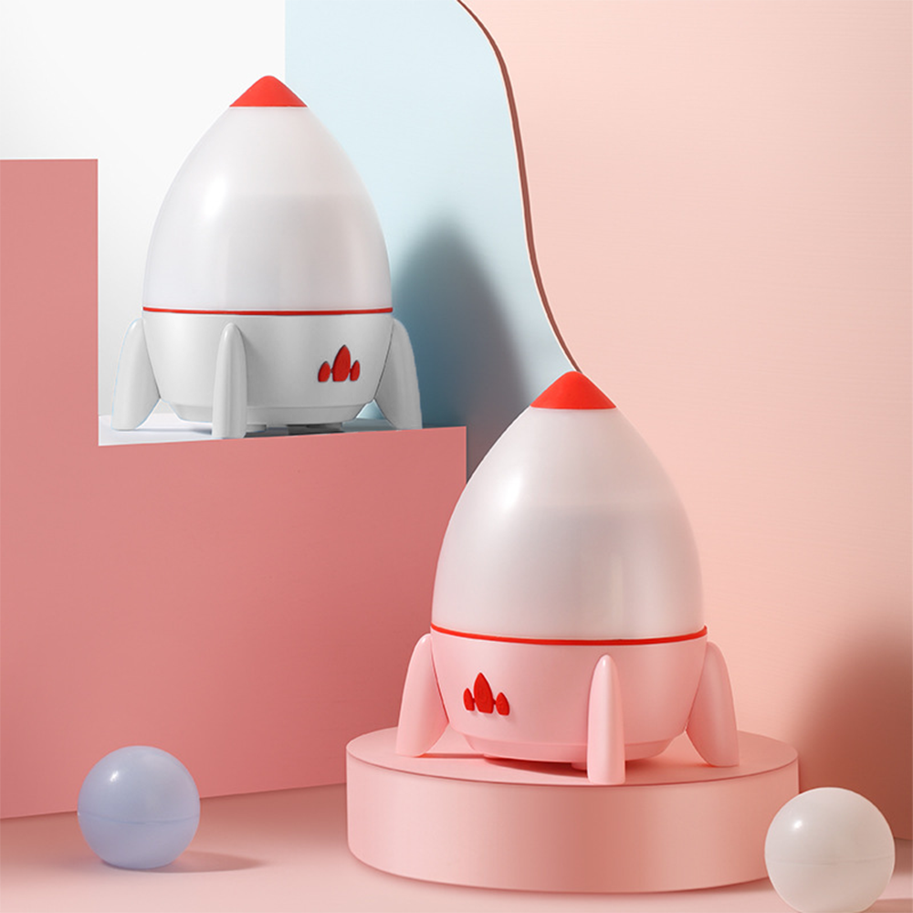 Zwei raketenförmige Lampen, eine weiß, eine rosa, mit roten Akzenten und eine blaue Kugel.