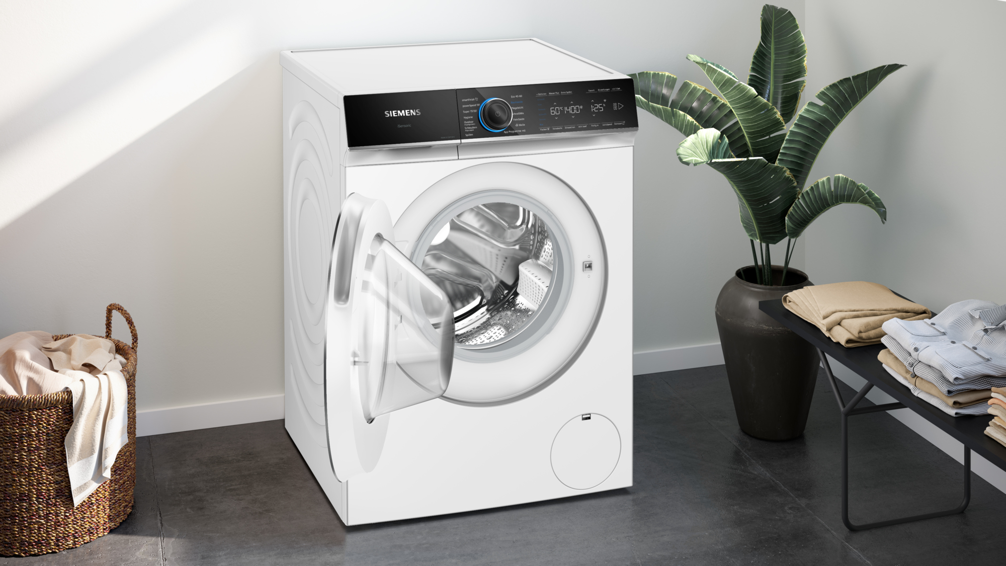 Weiße Siemens Waschmaschine mit offener Tür, neben Pflanze und Wäsche.