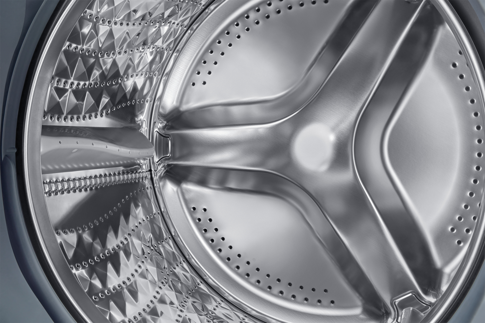 Intérieur d'un tambour de machine à laver en acier inoxydable, avec un motif et des trous.