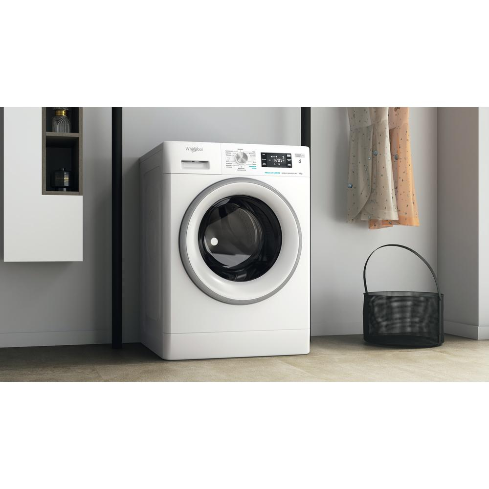 Weiße Whirlpool-Waschmaschine in einem Raum mit schwarzer Stange, Kleidern und einer Tasche.