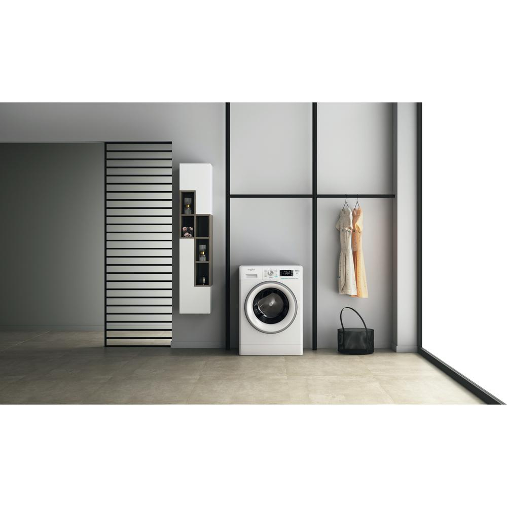 Eine weiße Waschmaschine in einem Waschraum, links ein Schrank und rechts eine Kleiderstange.