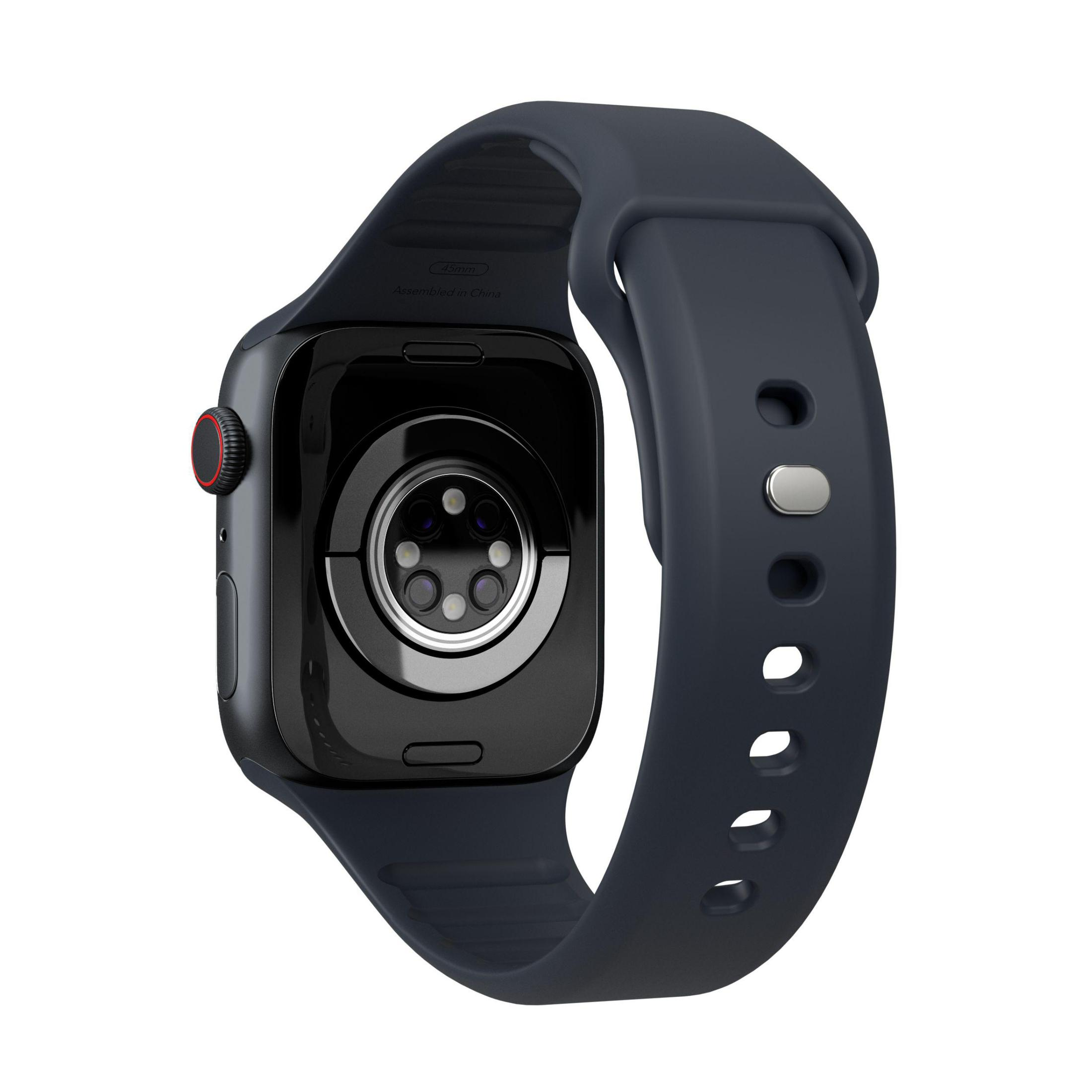 Primo piano del retro di uno smartwatch, con cinturino blu scuro. Presenta sensori di frequenza cardiaca e punti di ricarica.