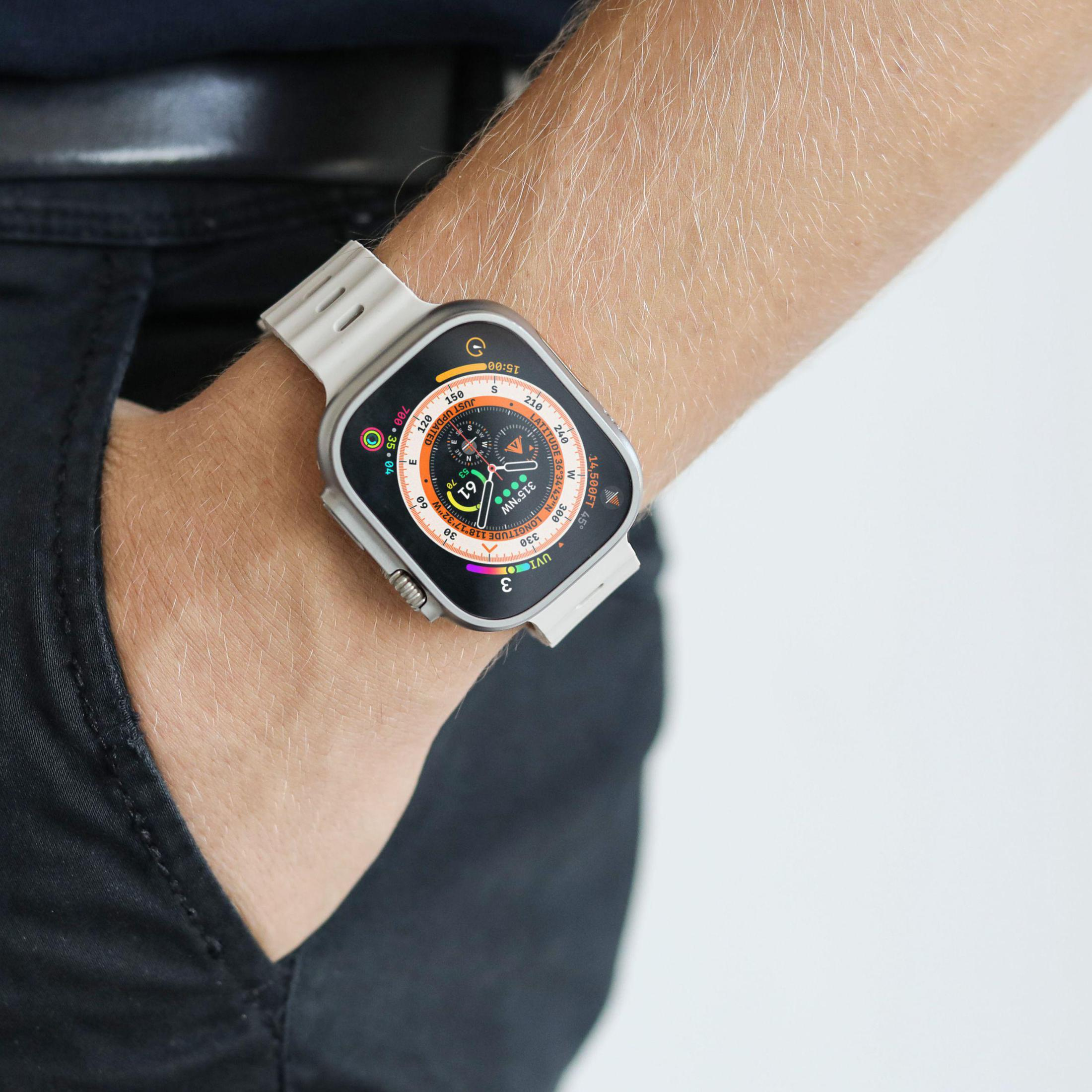 Osoba nosząca jasny smartwatch na nadgarstku, na neutralnym tle.