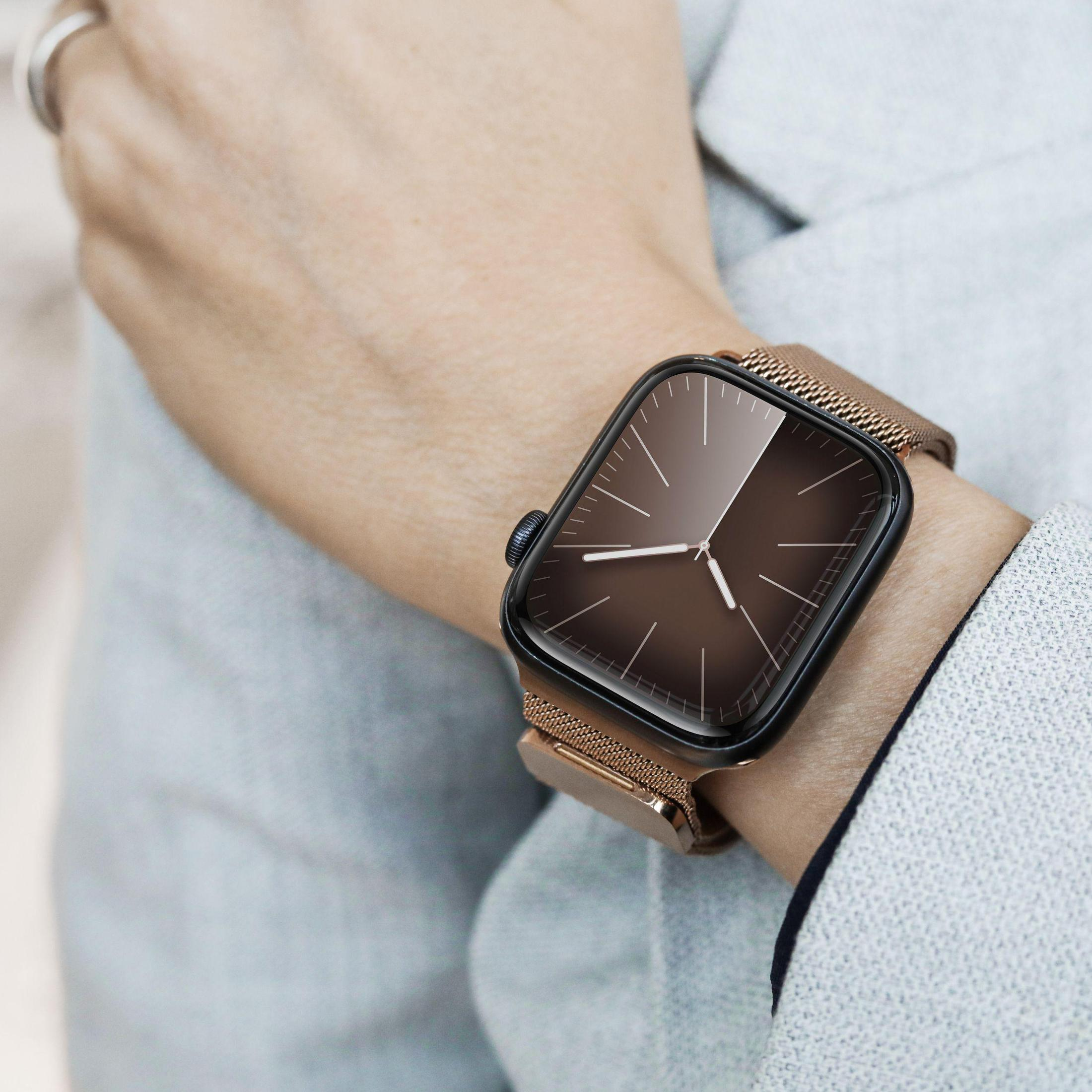 Nadarstek osoby z czarnym smartwatchem i złotym paskiem. Zegarek wyświetla ciemną tarczę.