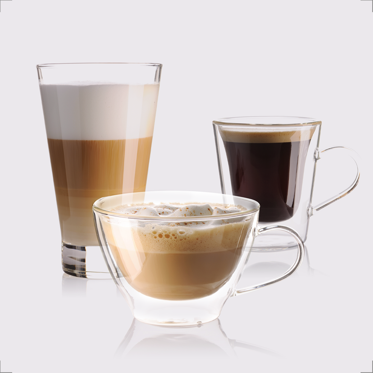 Three coffee drinks in transparent glass cups, on a white background.