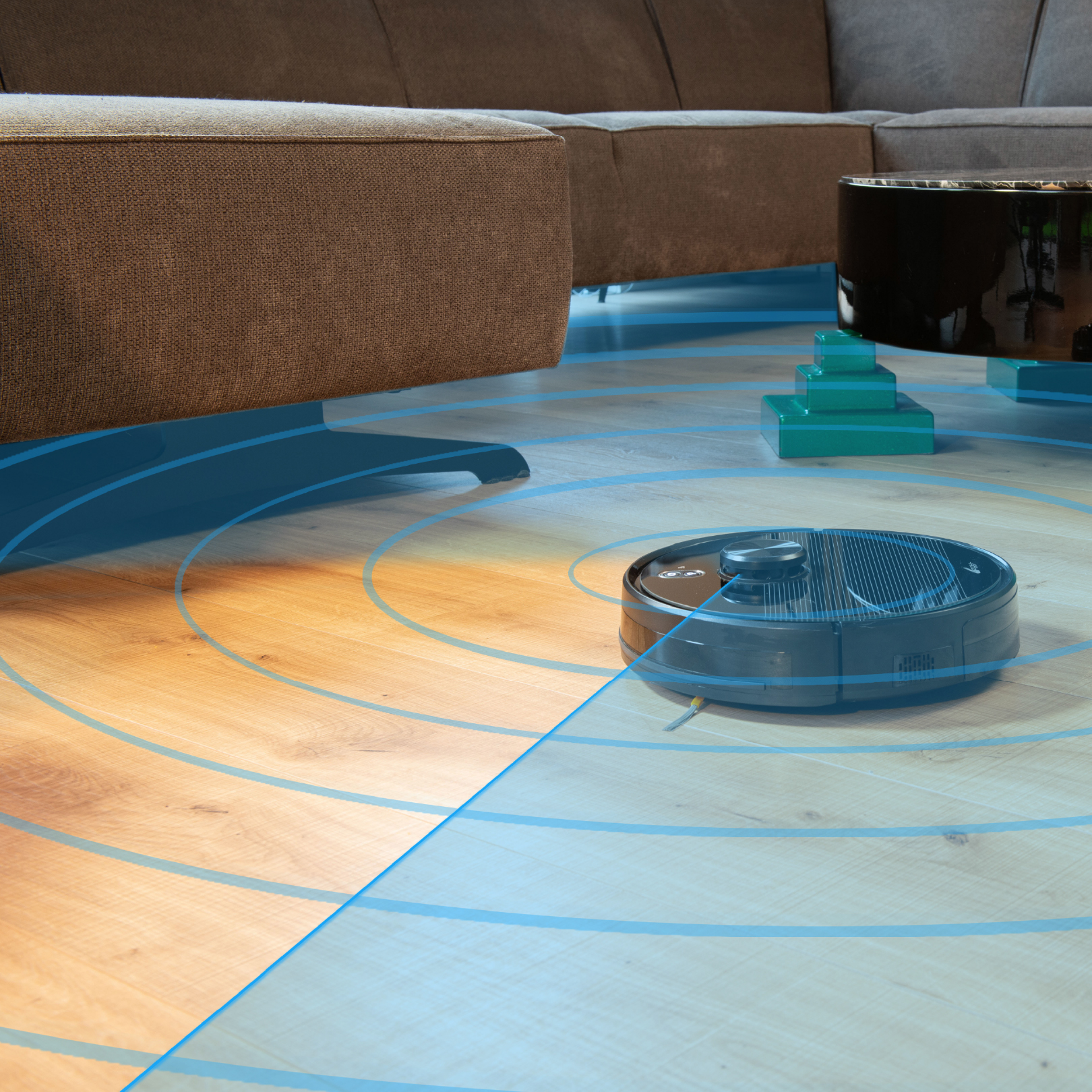 A black robot vacuum cleaner on a wooden floor. Blue circles show the cleaning area.