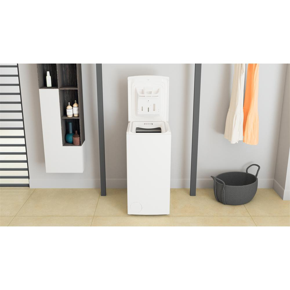 Biała pralka ładowana od góry w pokoju. Pokrywa jest otwarta.