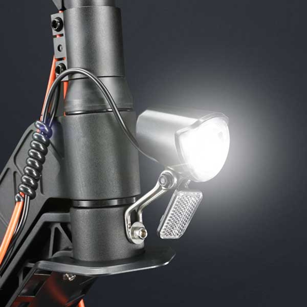 Fahrradscheinwerfer an einem schwarzen Roller montiert. Das Licht ist an, gibt einen hellen Strahl ab.