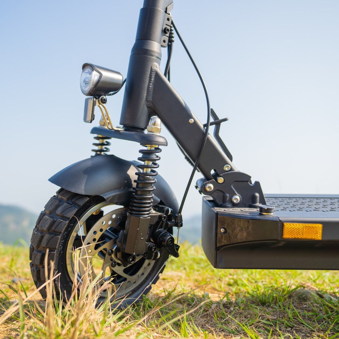 Vorderseite eines schwarzen Elektrorollers auf Gras. Beinhaltet Rad, Federung, Licht und einen Ständer.