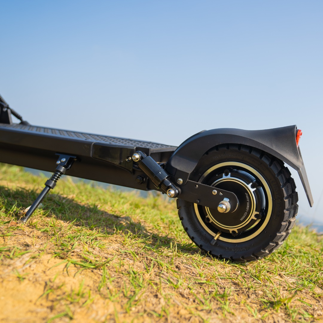 Schwarzer E-Roller auf Gras, Winkelansicht, Rad und Federung sichtbar.