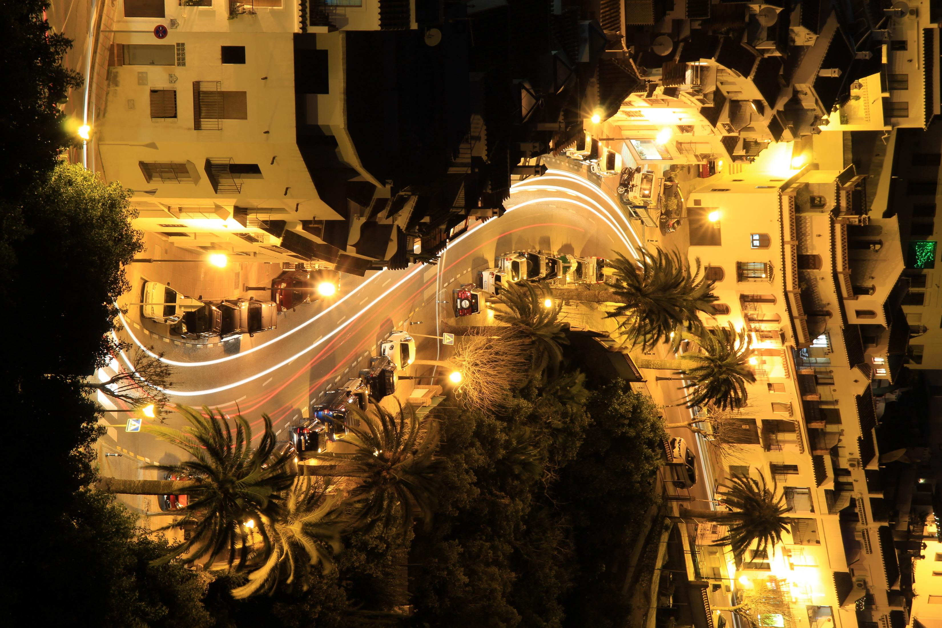 Night aerial view of a city street with streetlights and car light trails.