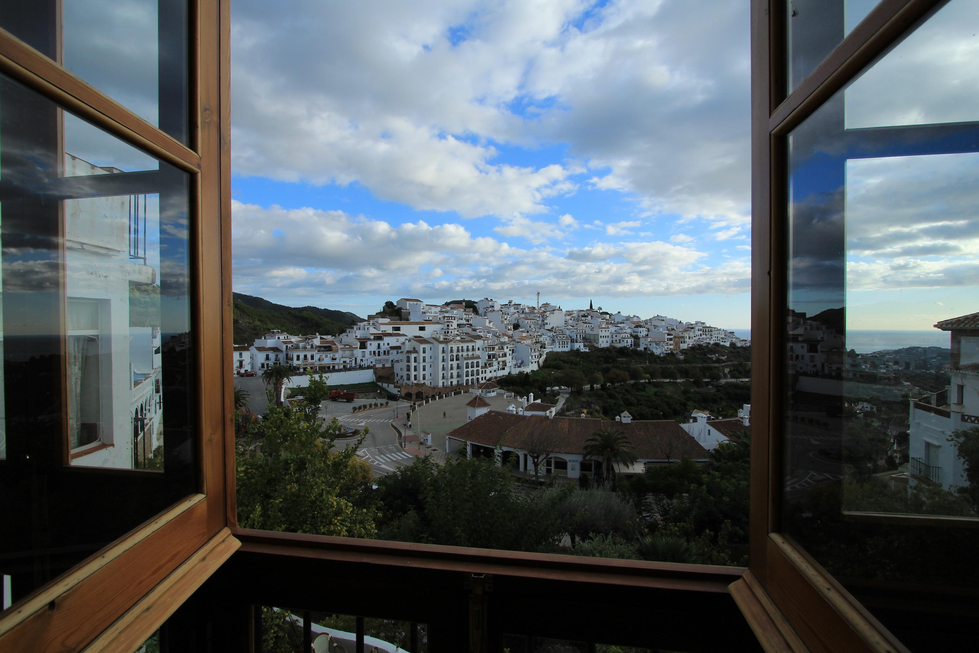 View from an open window of a white village on a hillside.