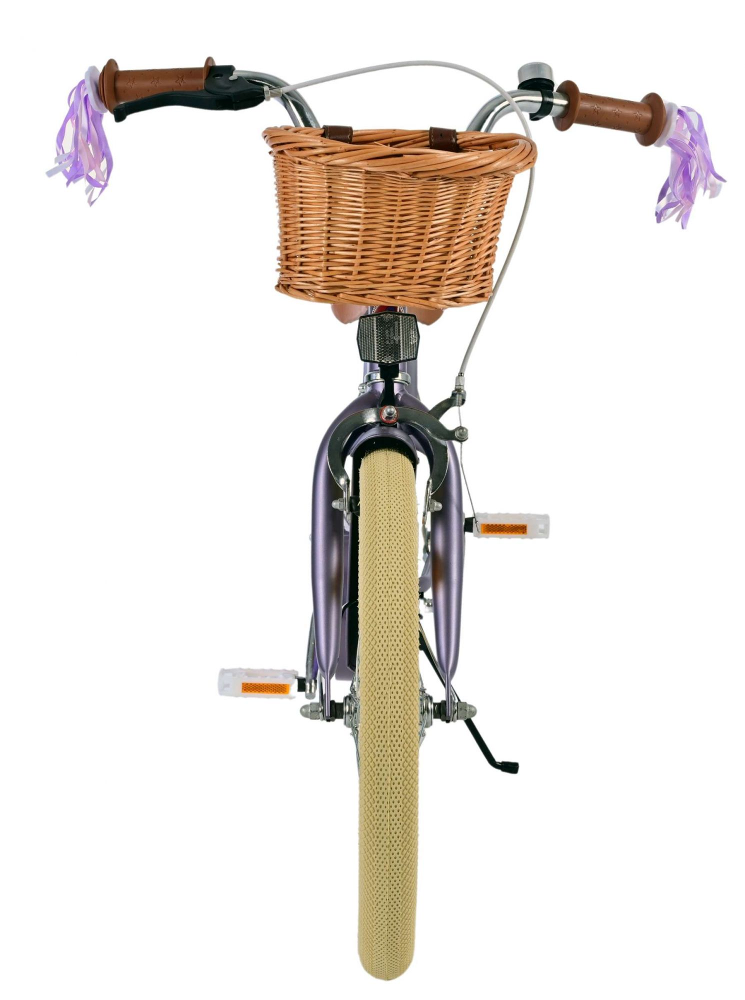 Vorderansicht eines lila Fahrrads mit Weidenkorb, cremefarbenen Reifen und Luftschlangen am Lenker.