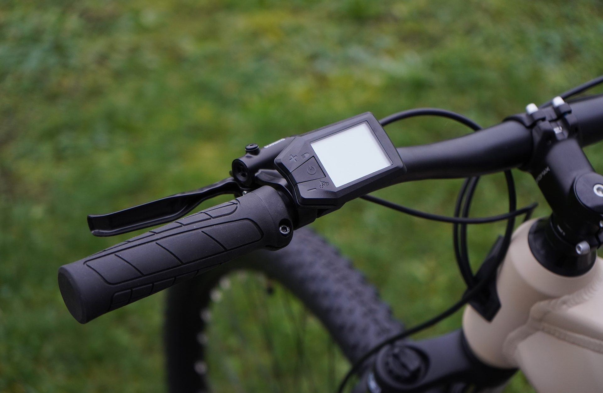 Nahaufnahme des Lenkers eines E-Bikes mit Display, auf grünem Hintergrund.