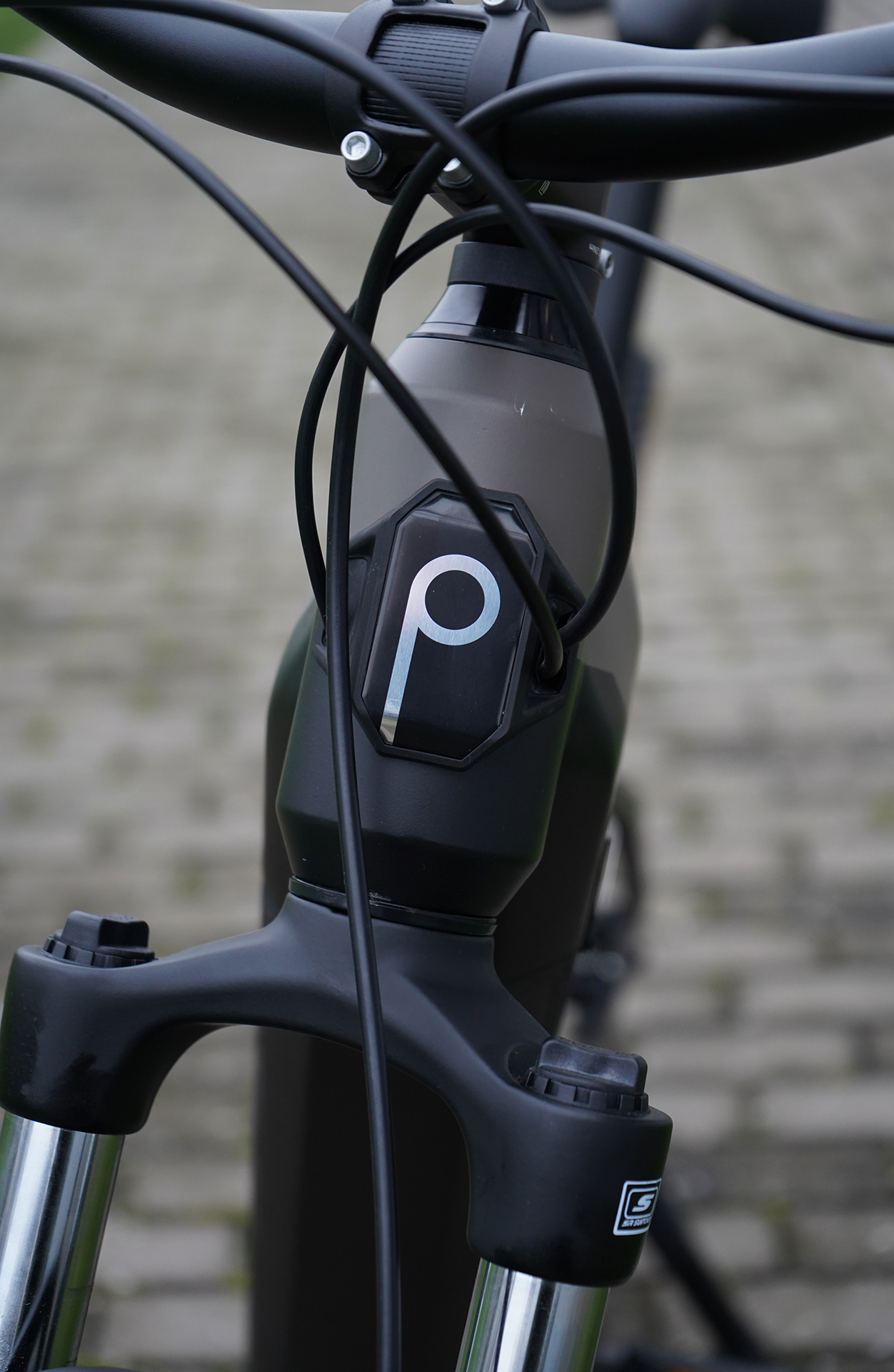 Nahaufnahme eines Fahrradlenkers und einer Vorderradgabel, wobei das Markenlogo sichtbar ist.