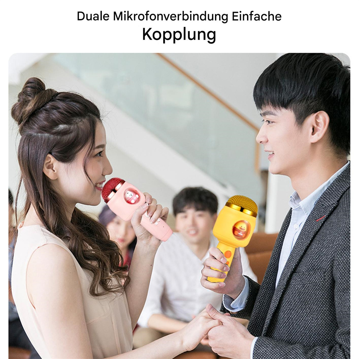 Zwei Personen halten rosa und gelbe Mikrofone, im Hintergrund eine Menschenmenge.