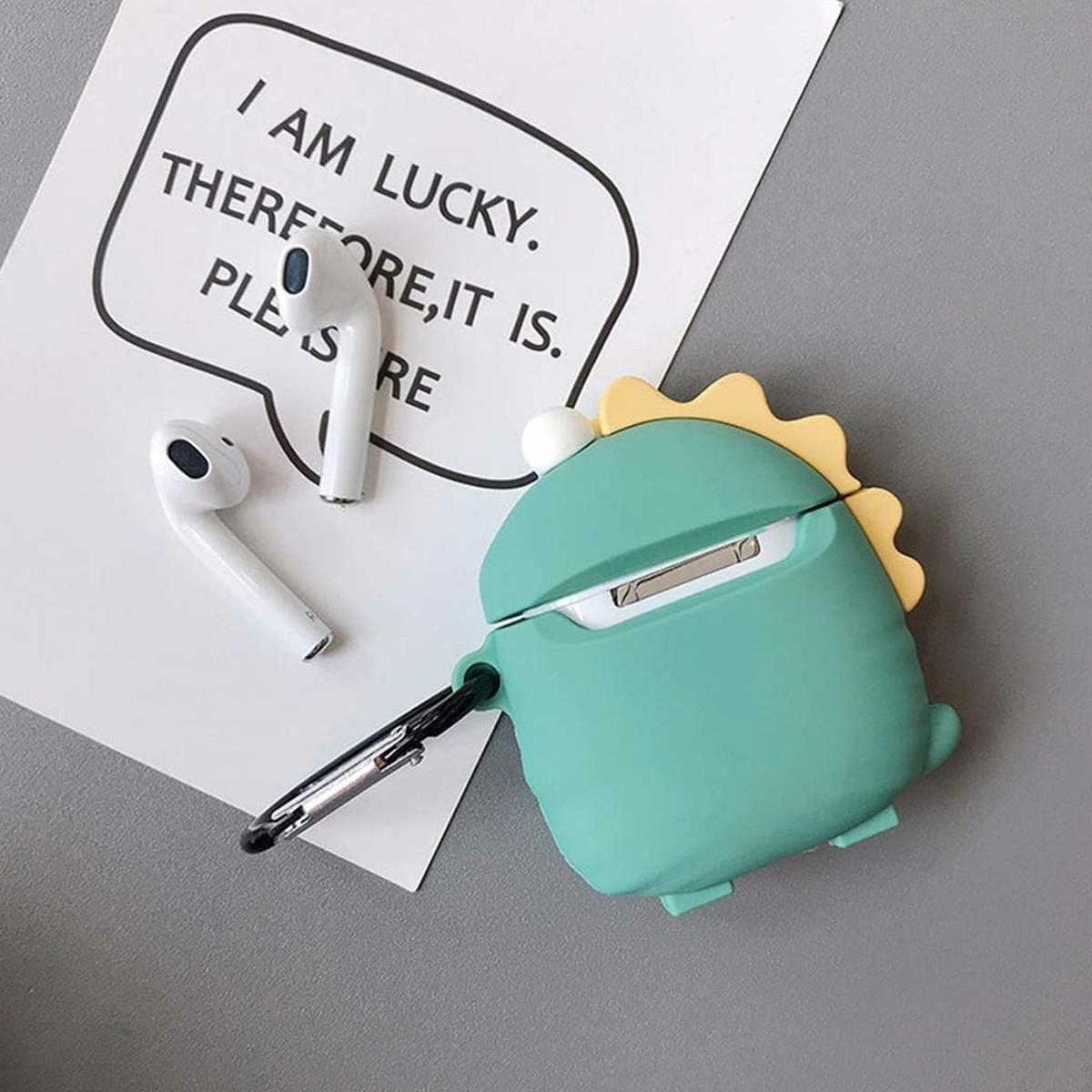 Airpods und eine Dinosaurier-förmige Hülle mit Schlüsselanhänger.