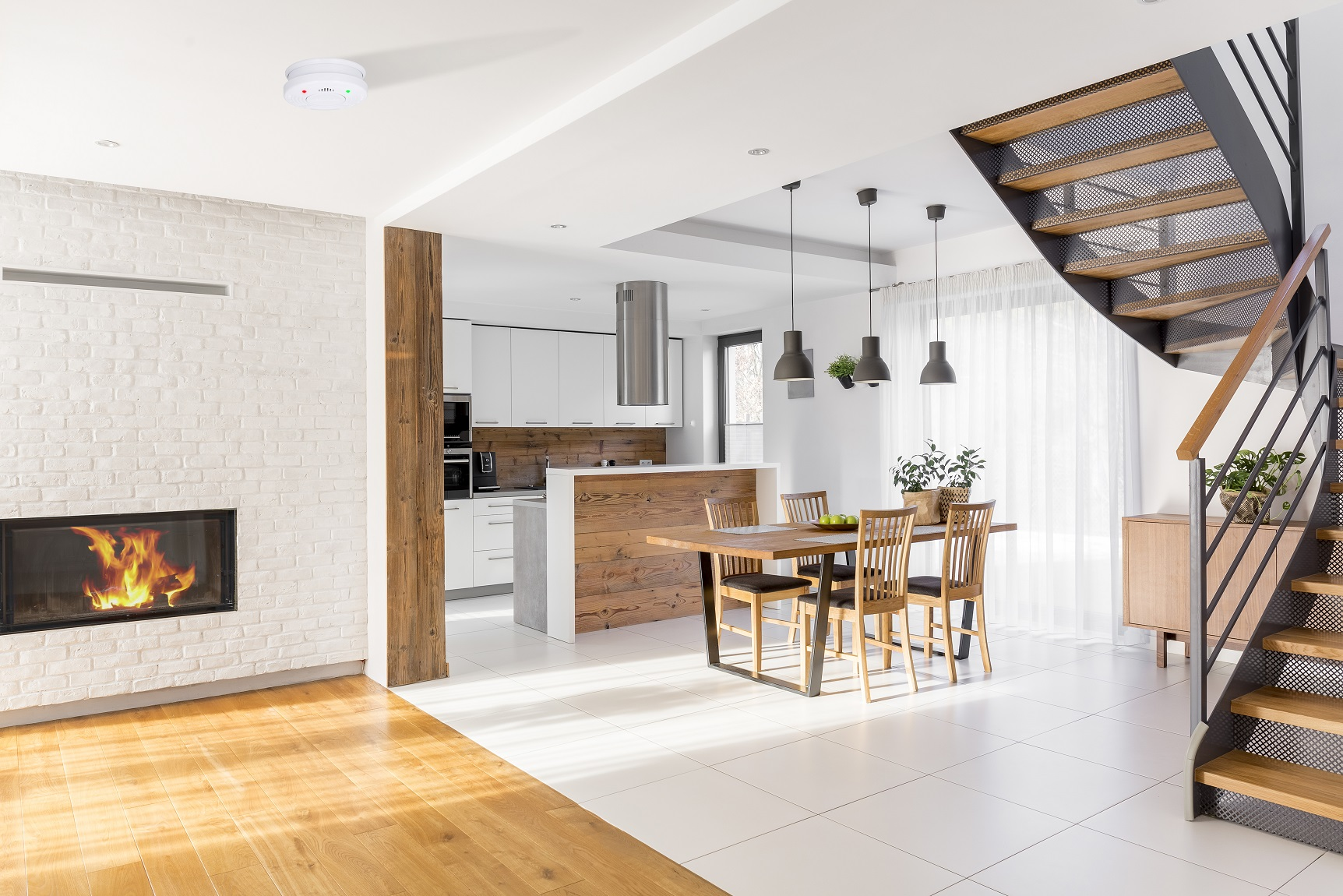 Modernes Wohnzimmer mit Kamin, Holzboden und Treppe, Küche im Hintergrund.