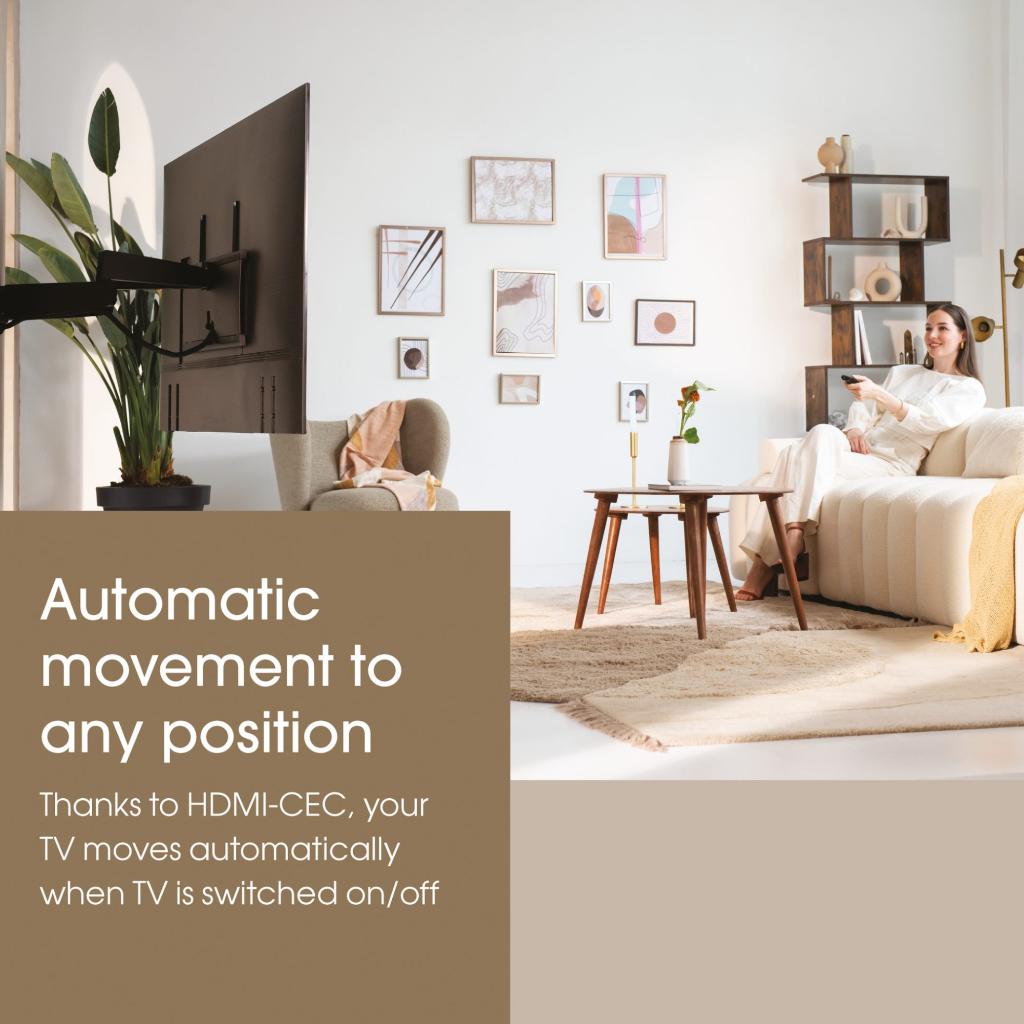 Kobieta w białej koszuli siedzi na kanapie i kieruje pilotem na telewizor zamontowany na ścianie.