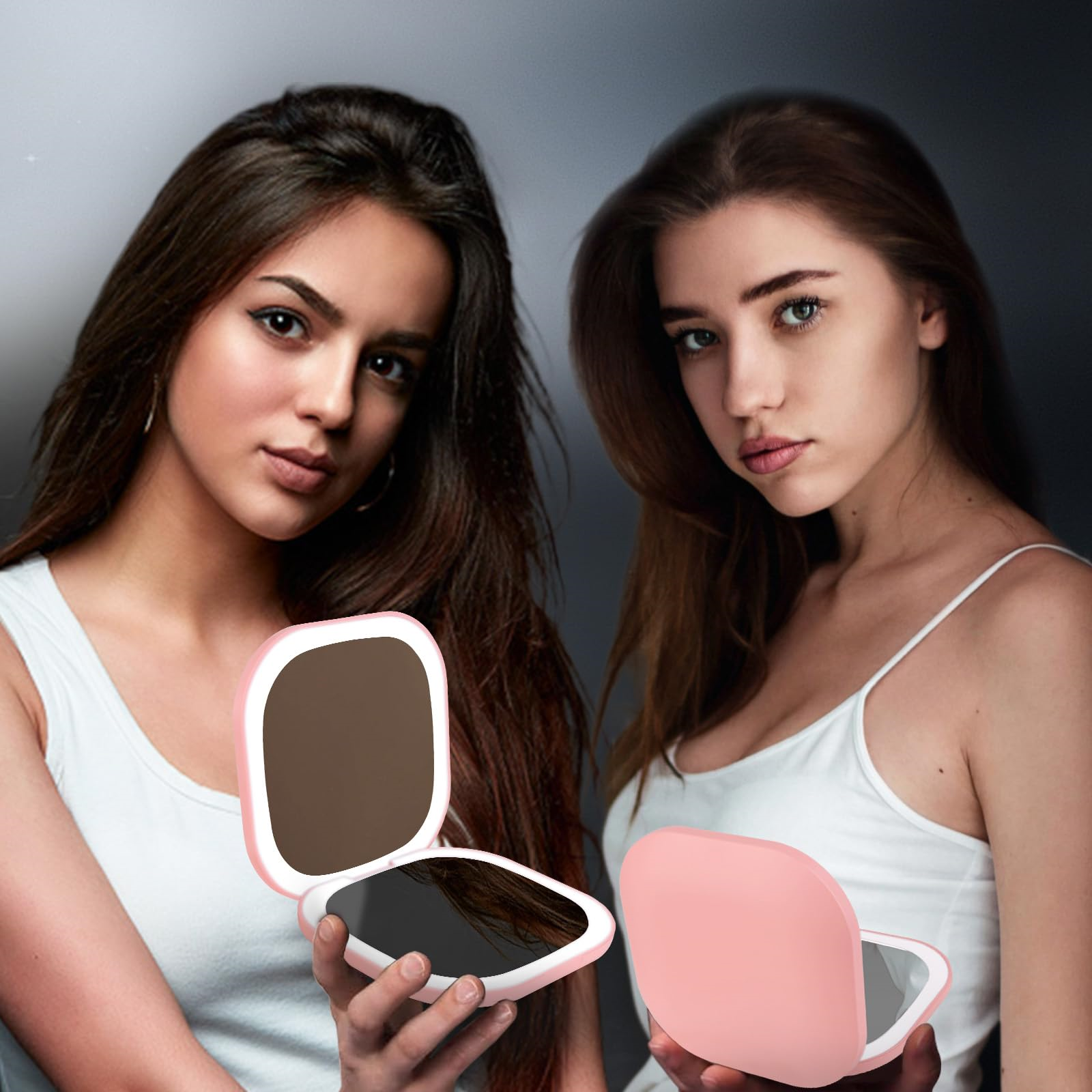 Zwei Frauen halten offene pinkfarbene Kompaktspiegel. Beide schauen in die Kamera.