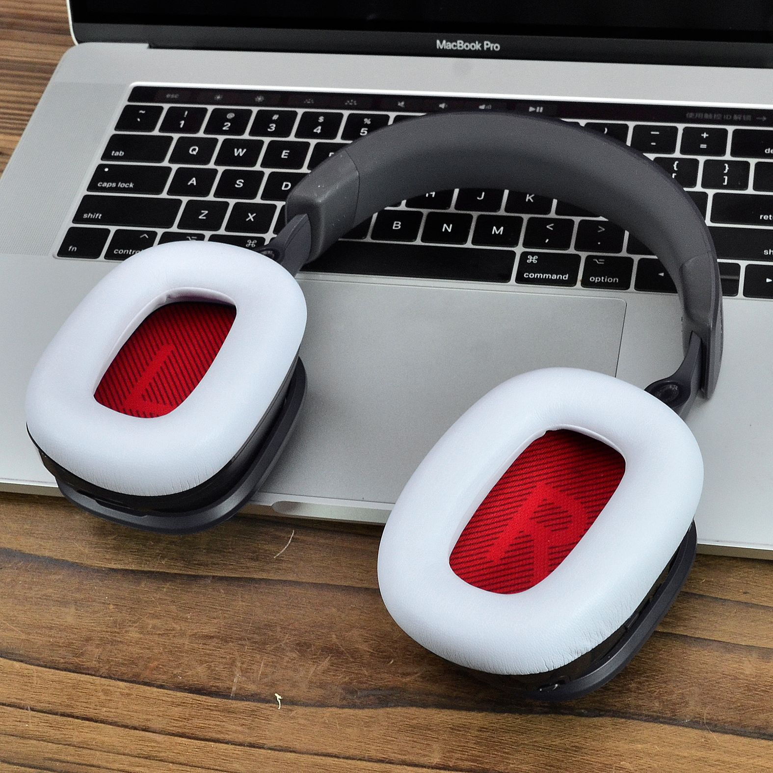 Słuchawki nauszne, białe nauszniki z czerwonym wnętrzem, na klawiaturze laptopa.