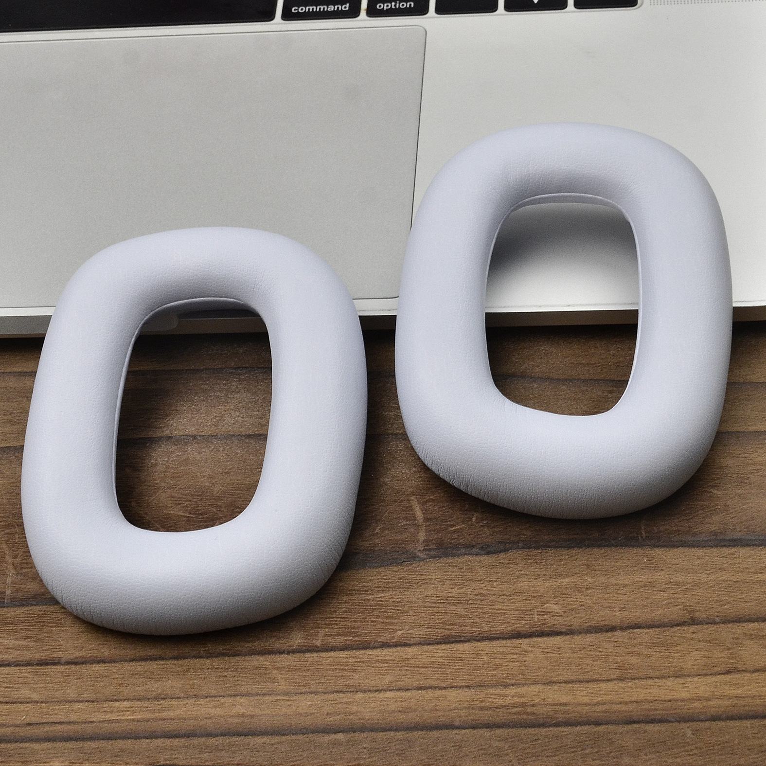 Dwie białe, owalne poduszki na uszy na klawiaturze laptopa.