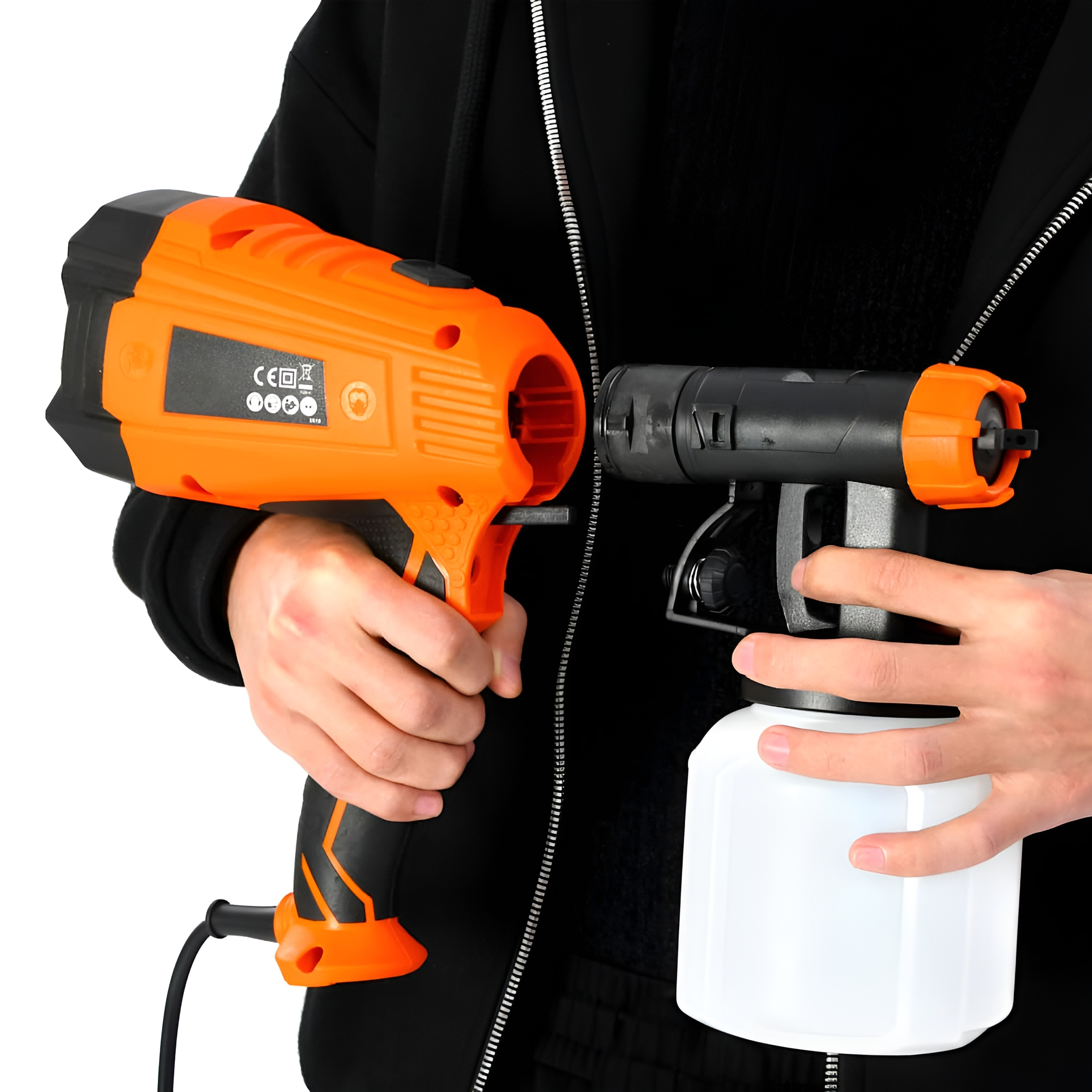 Eine Person, die eine orangefarbene und schwarze Spritzpistole mit einem daran befestigten weißen Behälter hält.