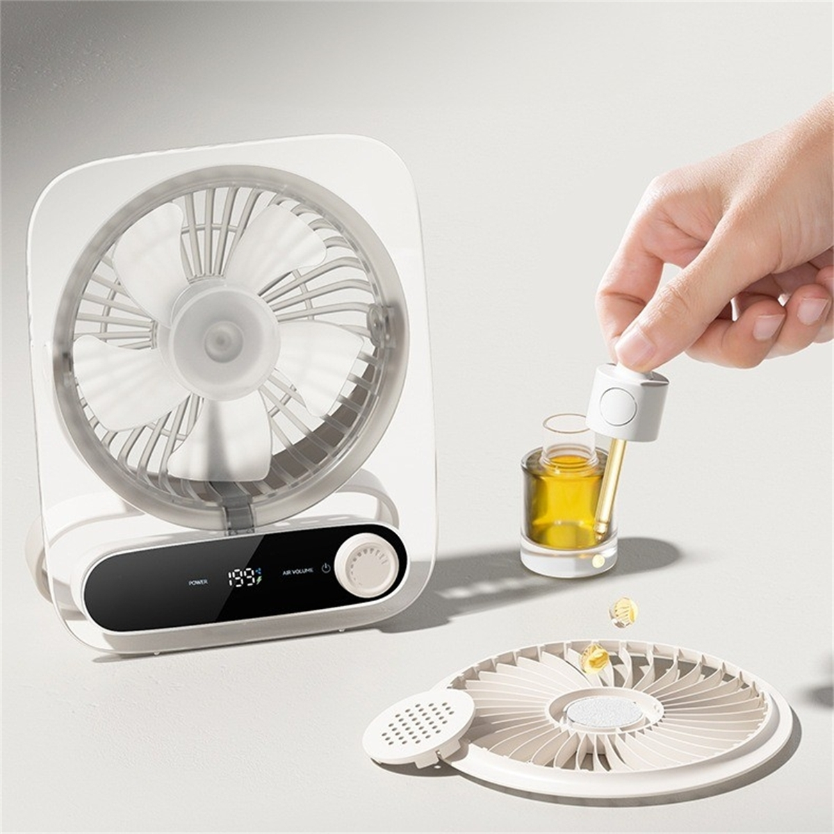 Weißer Ventilator mit einer Hand, die Öl in einen Diffusor gibt. Weitere Ventilatorteile sichtbar.