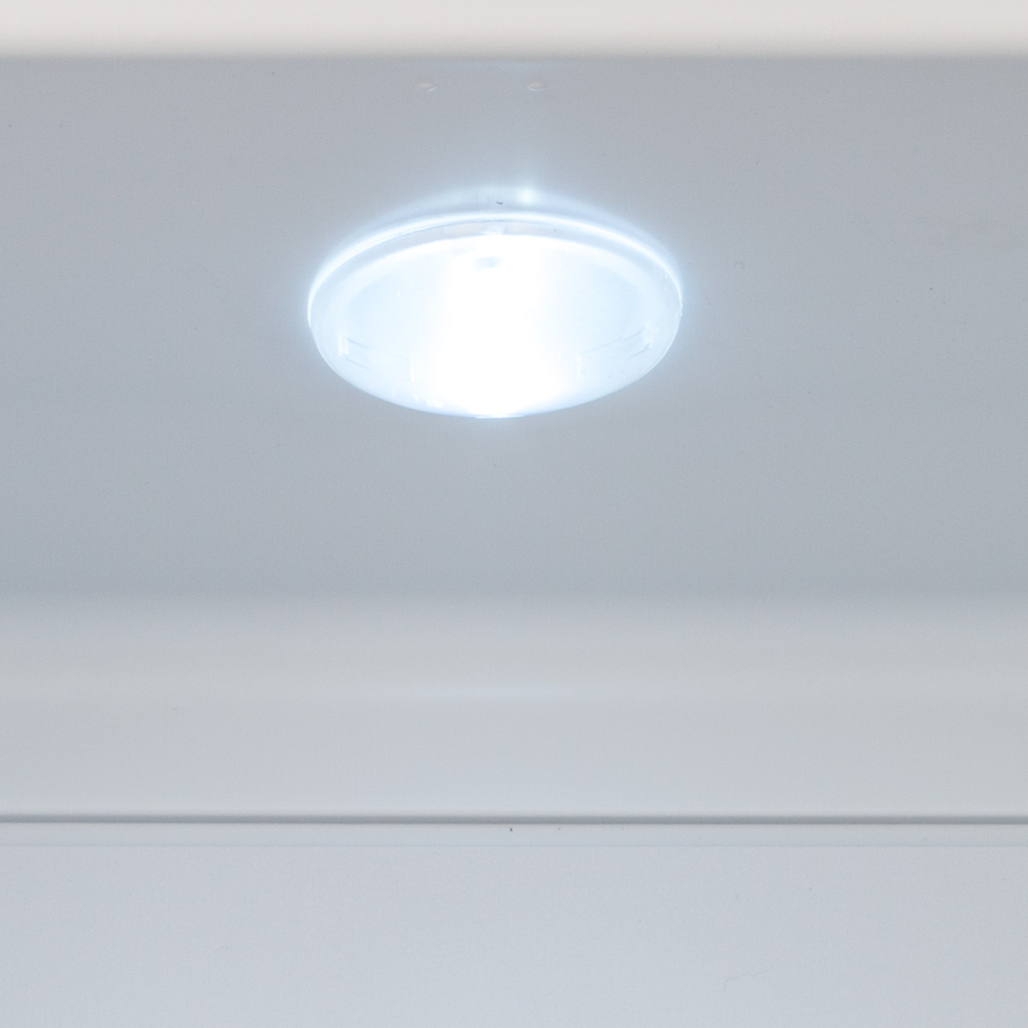 Primo piano di una luce circolare brillante all'interno di un frigorifero. Bianco e luminoso.