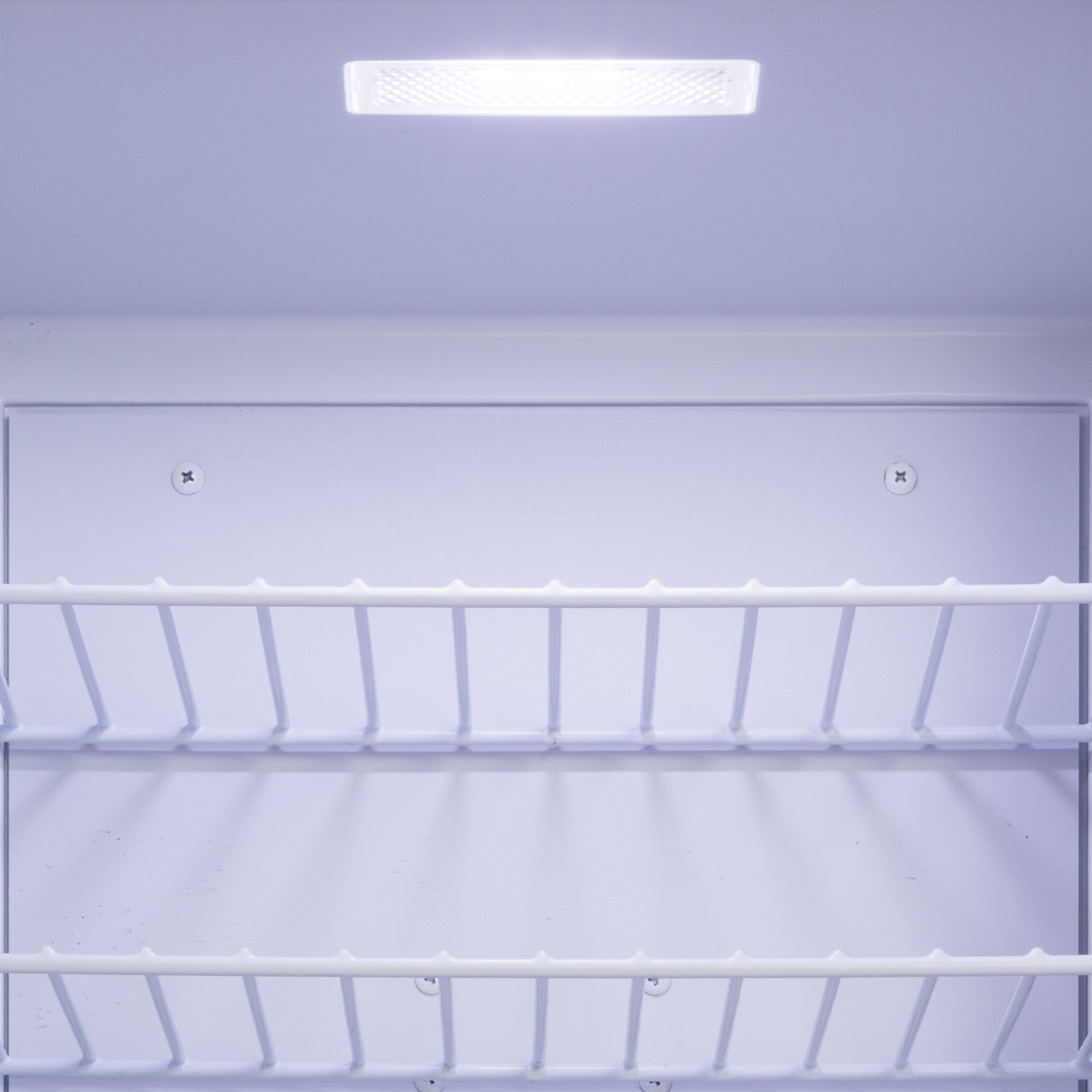 All'interno di un frigorifero bianco. Due ripiani in filo, una luce e un interno bianco. Nessun cibo visibile.